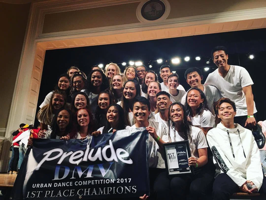 Group of young dancers holding a banner on stage, celebrating their first place win at the 2017 Prelude DMV Urban Dance Competition.