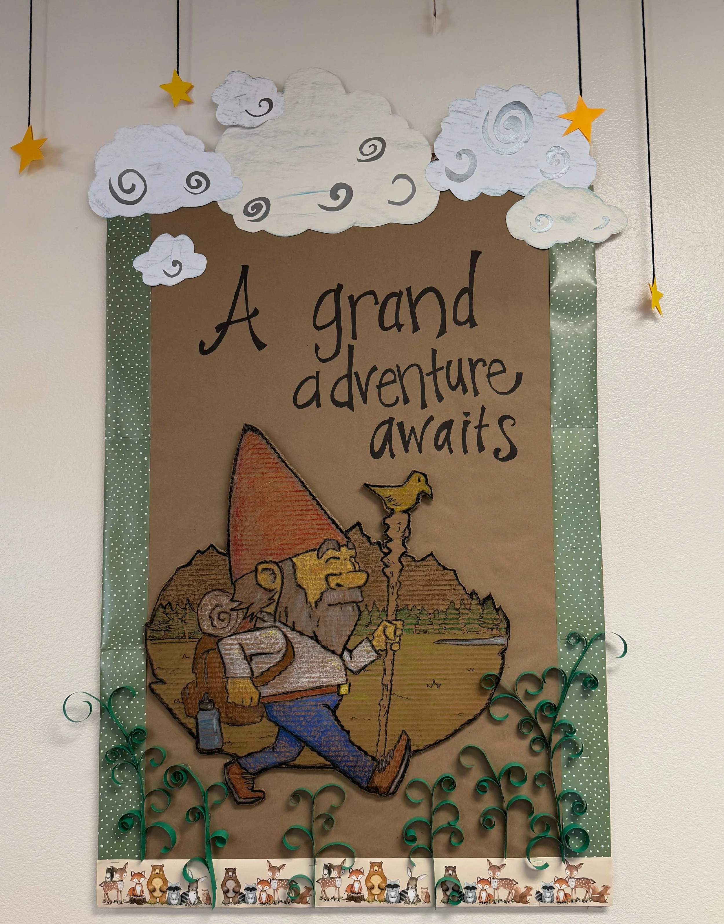 A decorated poster with cartoon clouds and stars, reading 'A grand adventure awaits', featuring a cartoon hiker with a backpack, walking with a walking stick in a nature scene.