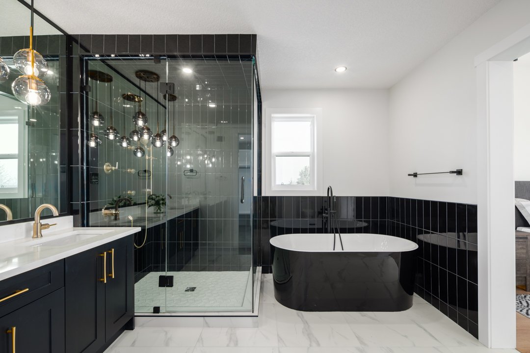 Modern bathroom with black and white color scheme, featuring a freestanding black bathtub, a glass-enclosed shower, and a vanity with gold fixtures.