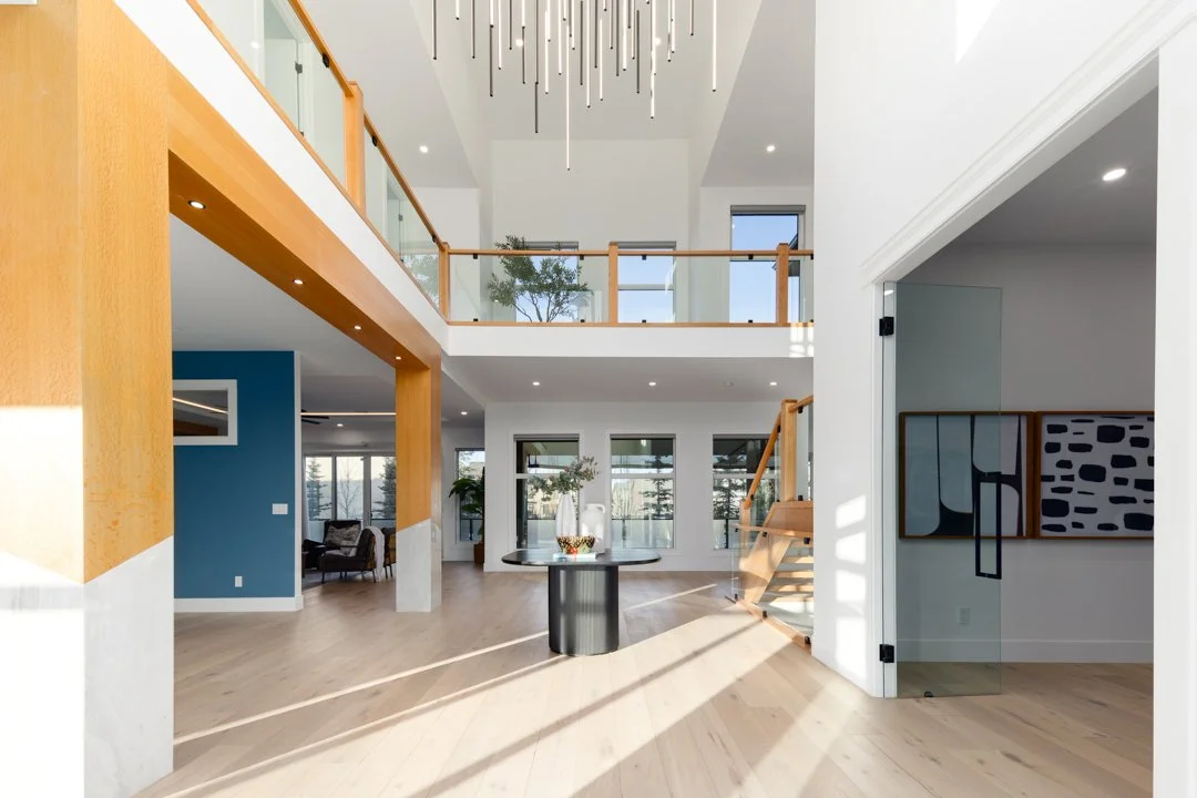 Spacious modern home interior with high ceilings, wooden accents, large windows, and minimalistic decor.