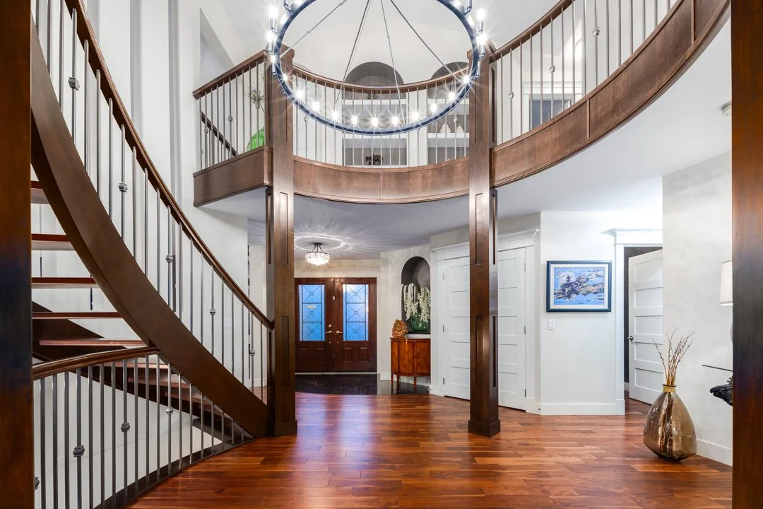Interior of a home featuring a wooden spiral staircase, elegant chandelier, and modern decor near the entrance.