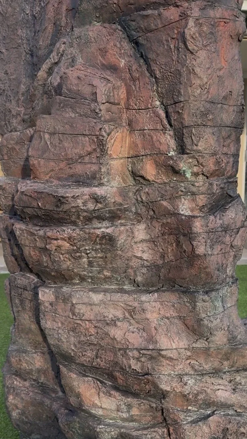 Close-up of a large, textured reddish-brown rock formation with visible cracks and layers.