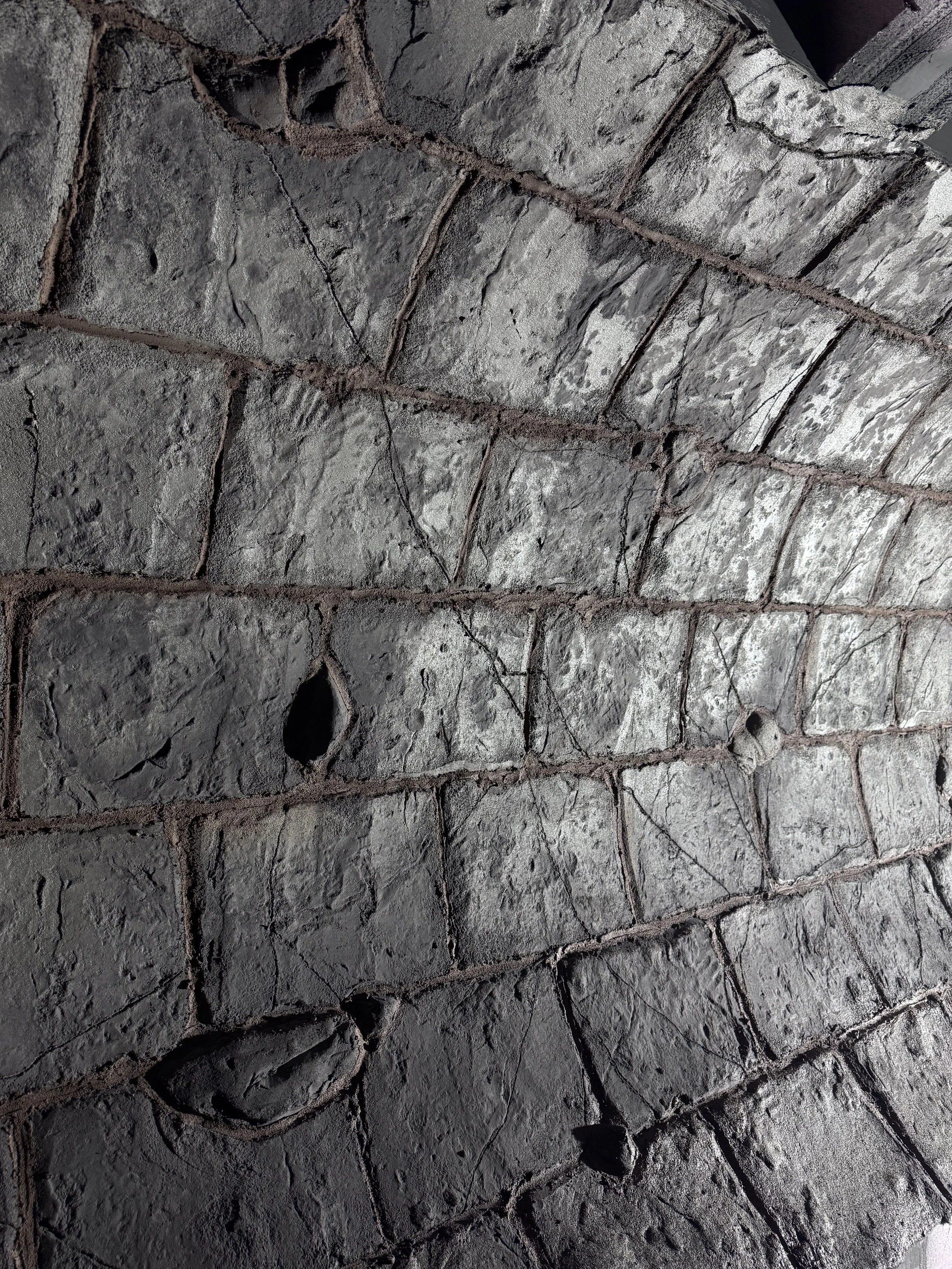 Close-up of a weathered brick wall with holes and cracks.