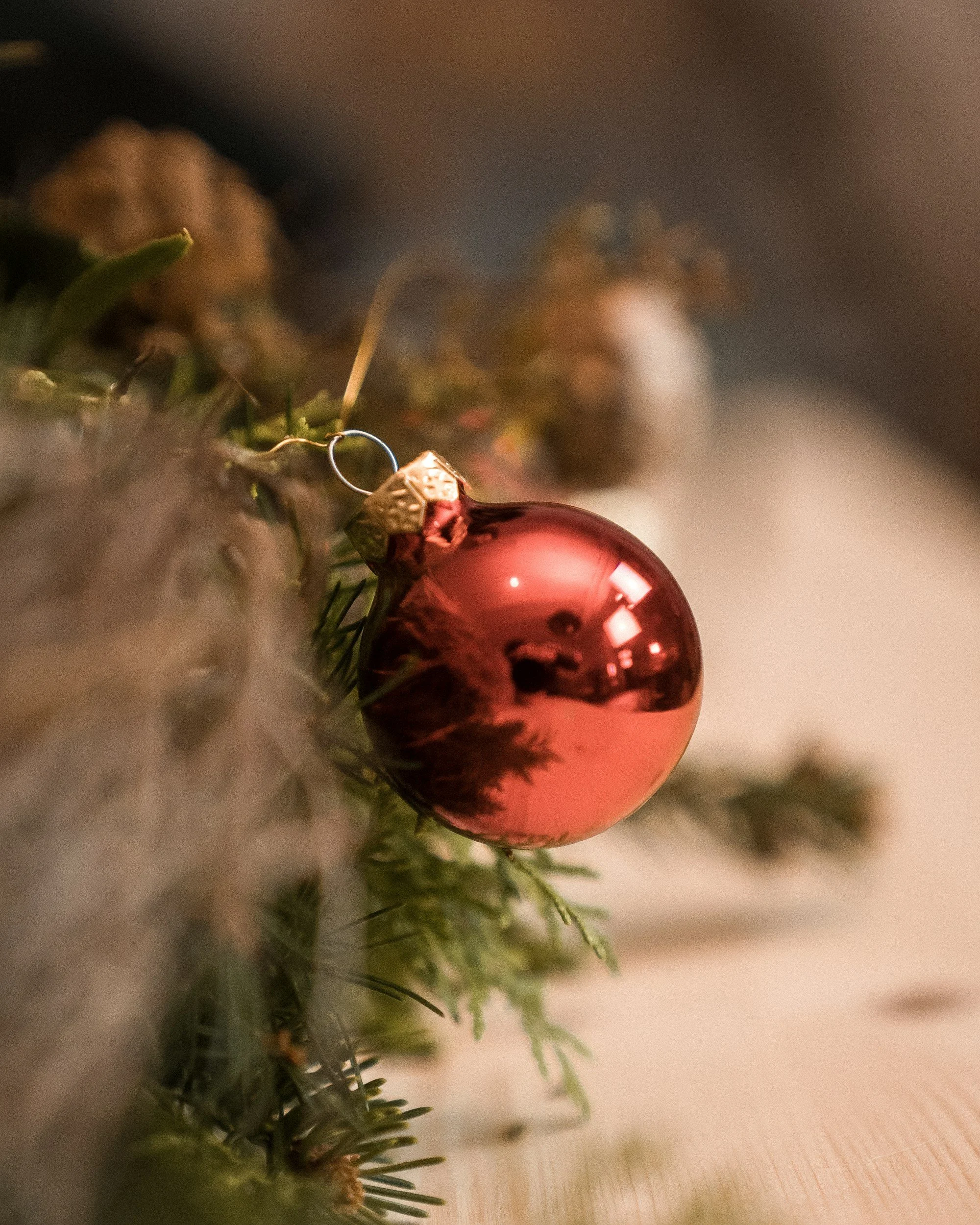 Close-up of a shiny red Christmas ornament hanging on a Christmas tree branch.
