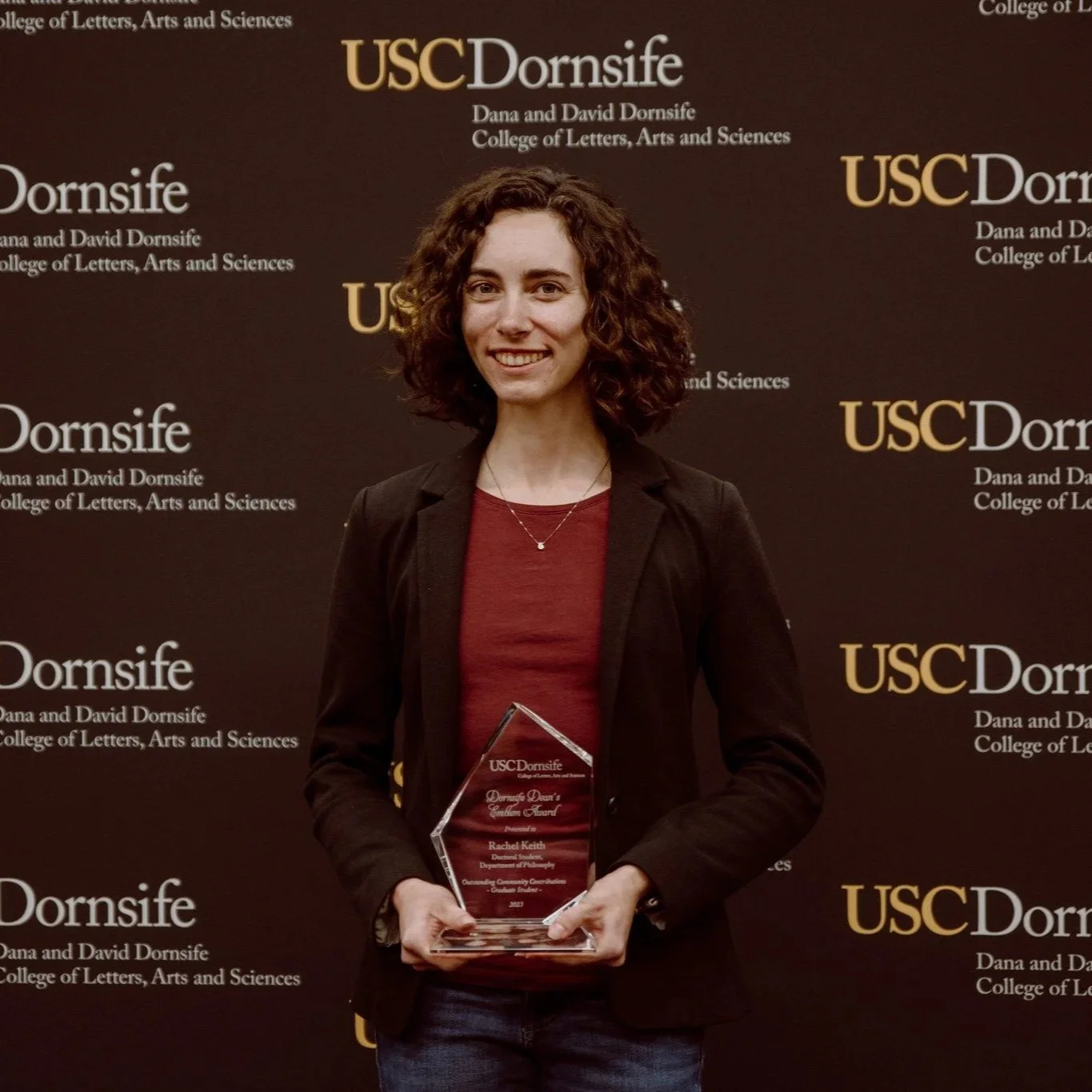 Rachel Higginbotham holding an award for outstanding community contributions awarded by the dean of USC Dornsife