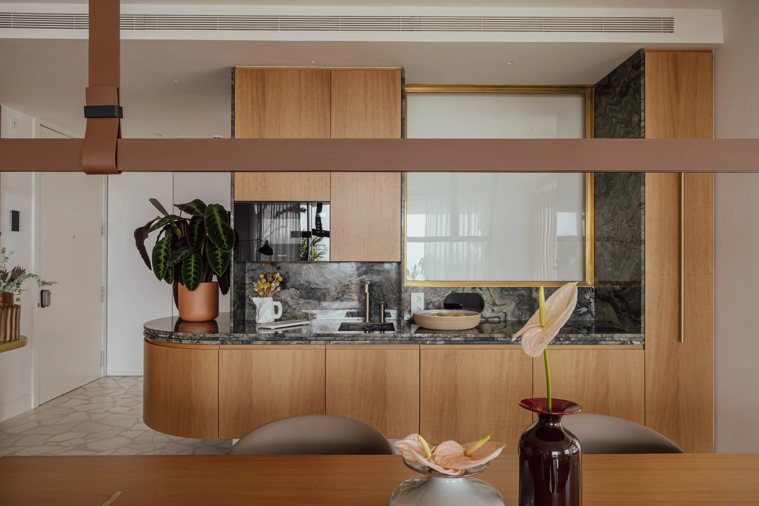 Modern kitchen with wooden cabinets, marble countertop, and a large window.
