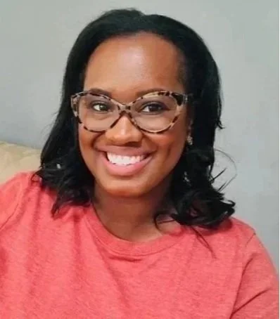 Smiling woman with glasses and curly hair wearing a red shirt
