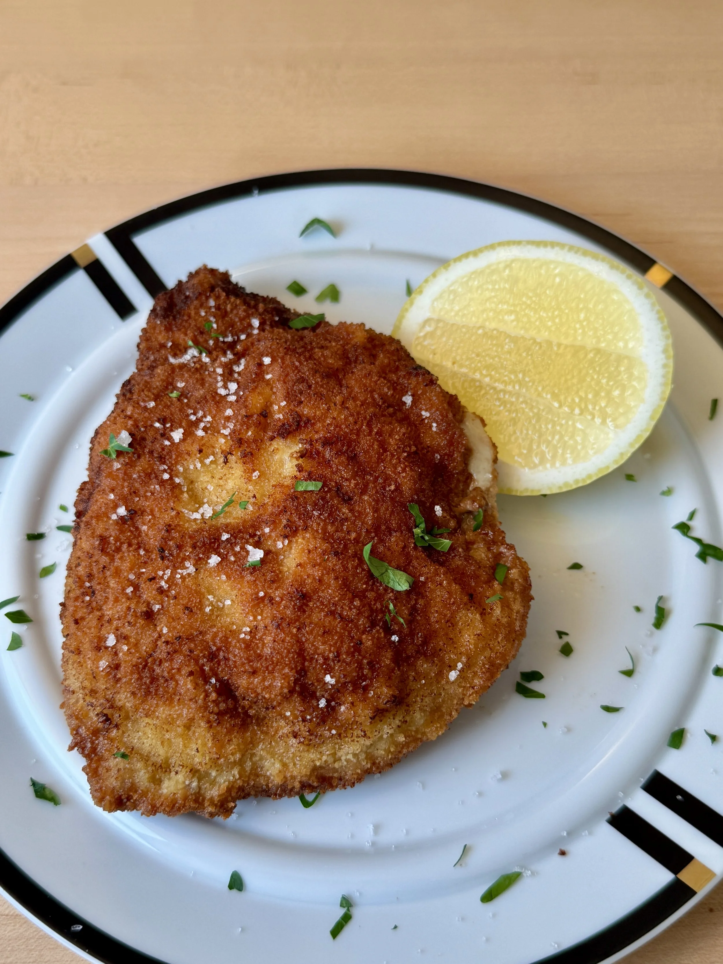 Cordon Cleu on a plate with lemon wedge and parsley.