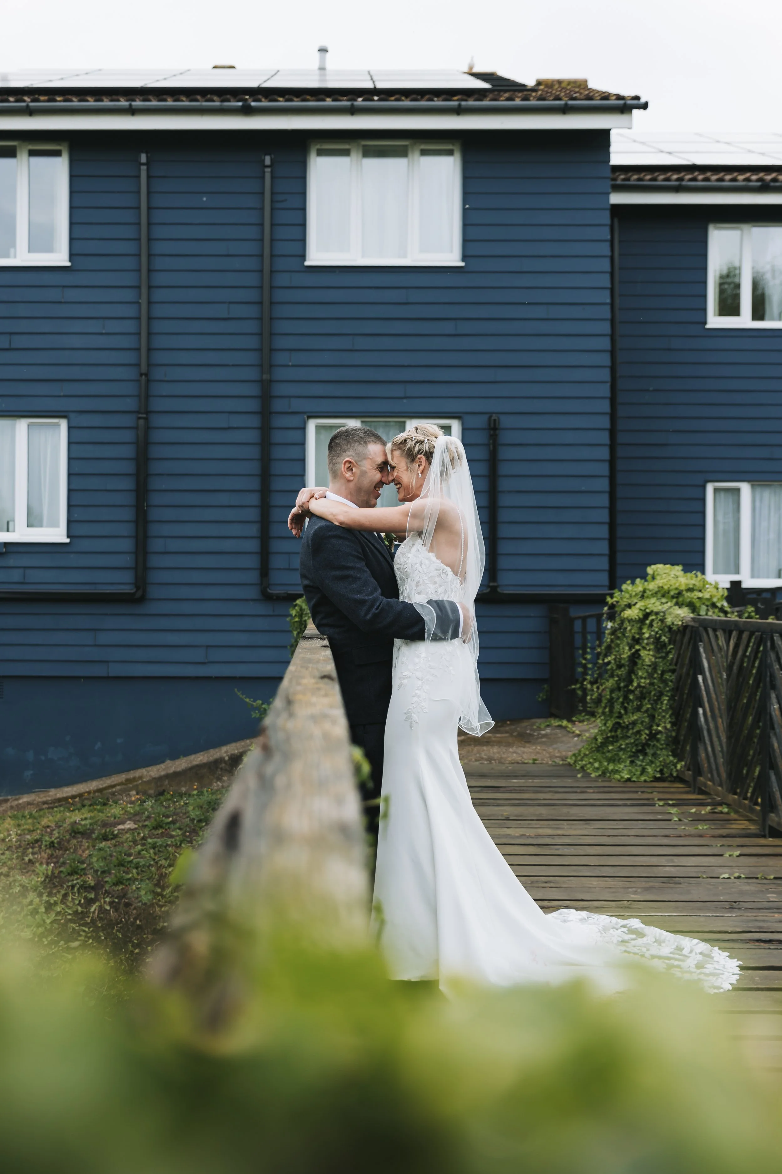 A bride and groom embrace on footbridge at Bridge House Hotel, Dorset.