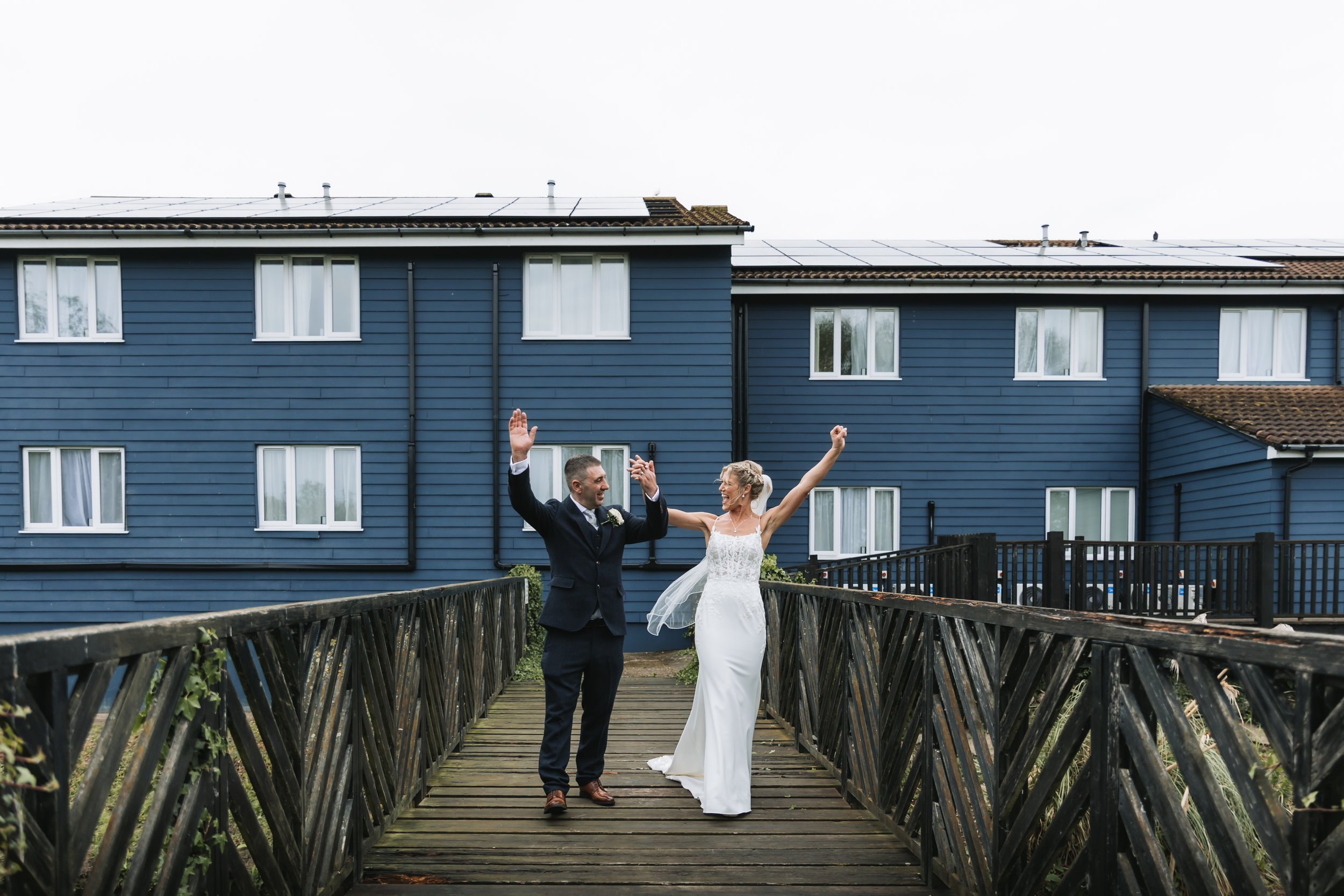 Bride and groom celebrating on footbridge at Bridge House Hotel, Ferndown in Dorset.
