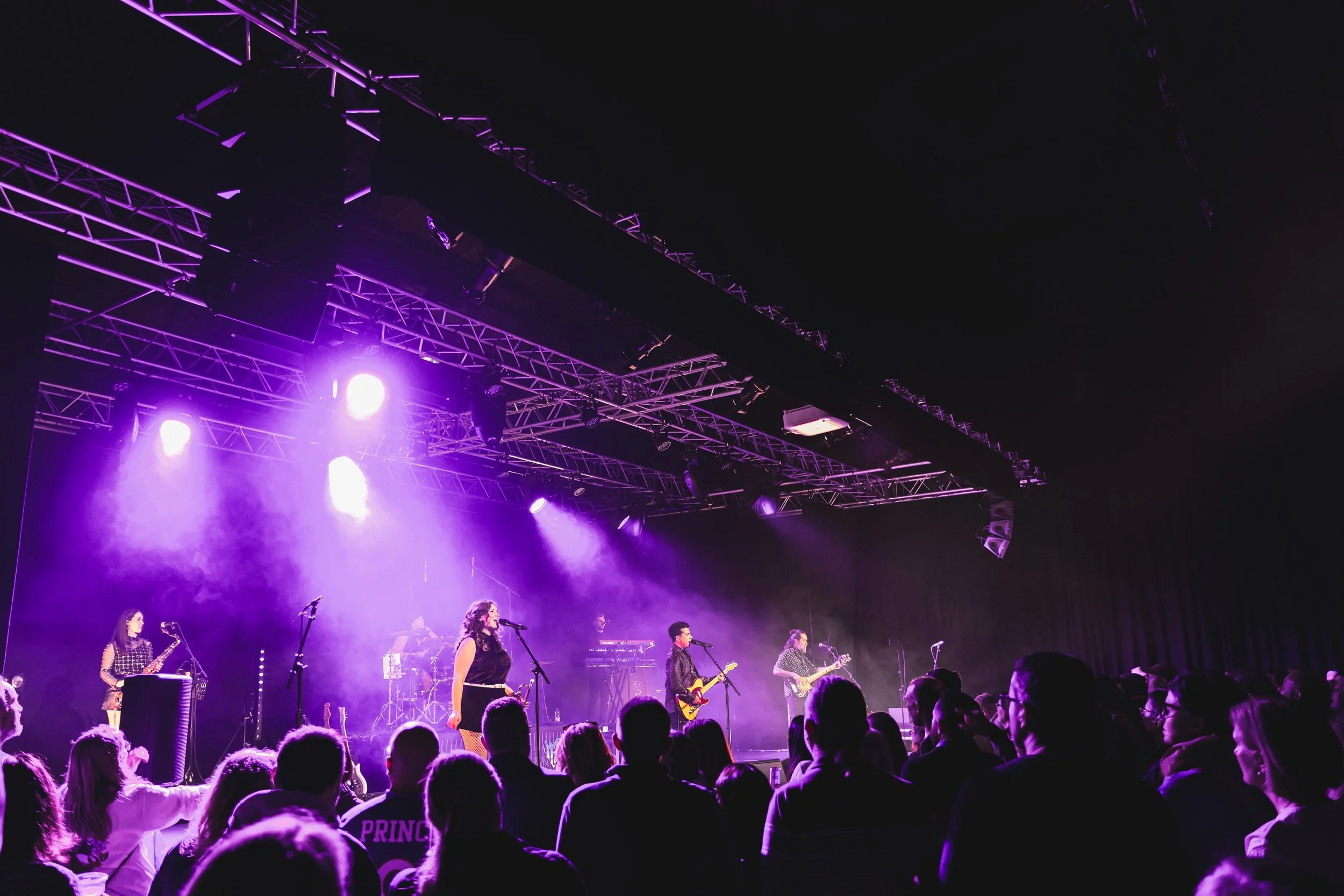 Prince tribute act, New Purple Celebration performing on stage in Ringwood, Dorset with purple lighting.