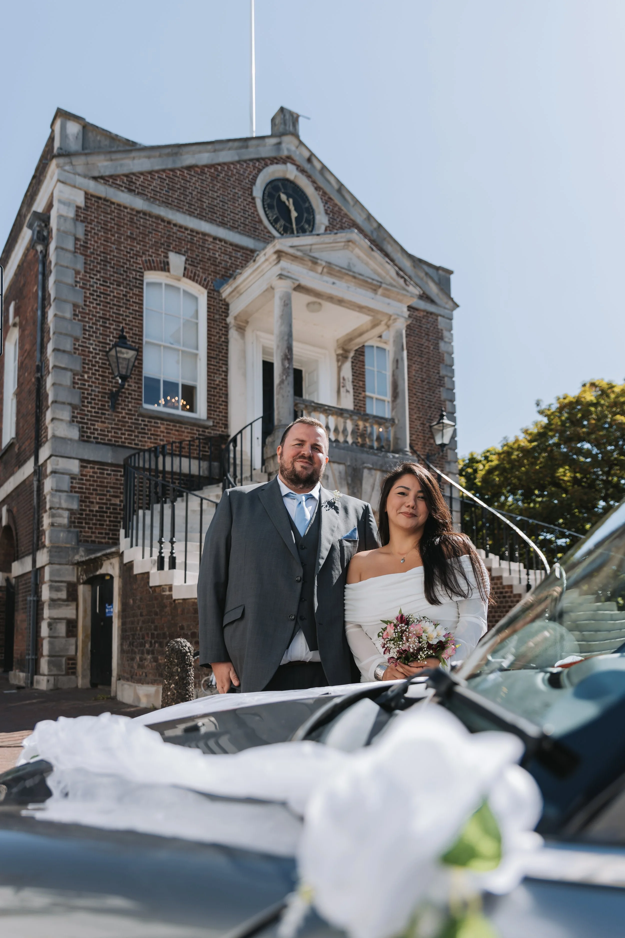 Bride and groom portrait with car outside Poole Guildhall, Dorset.