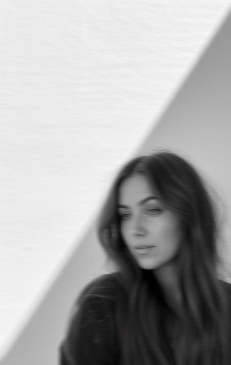 Black and white photo of a woman with long hair posing against a wall, with a triangle-shaped shadow creating a geometric background.