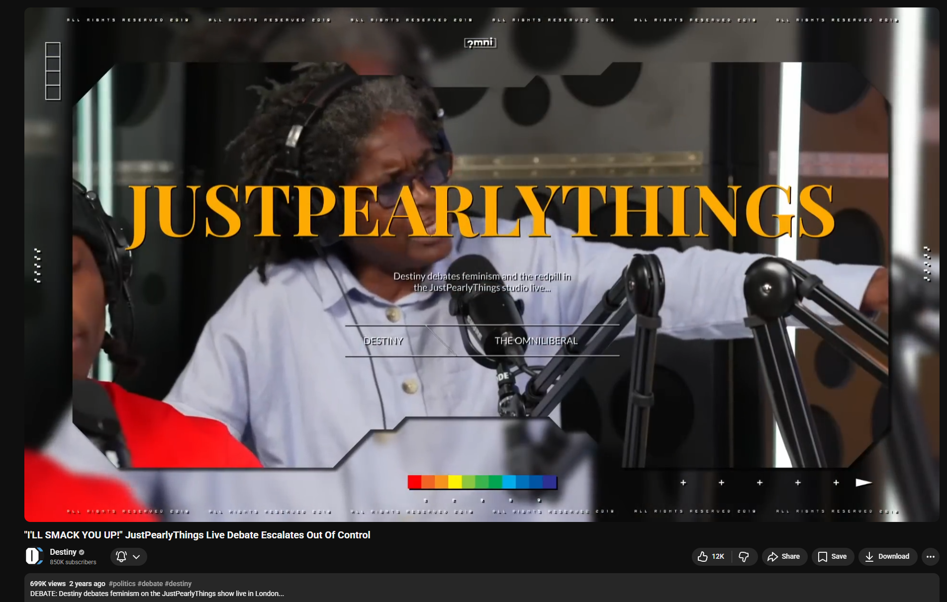 A woman with curly hair wearing headphones and a white shirt speaking into a microphone during a live debate in a studio, with the text 'JUSTPEARLYTHINGS' overlayed in large orange letters in the center.