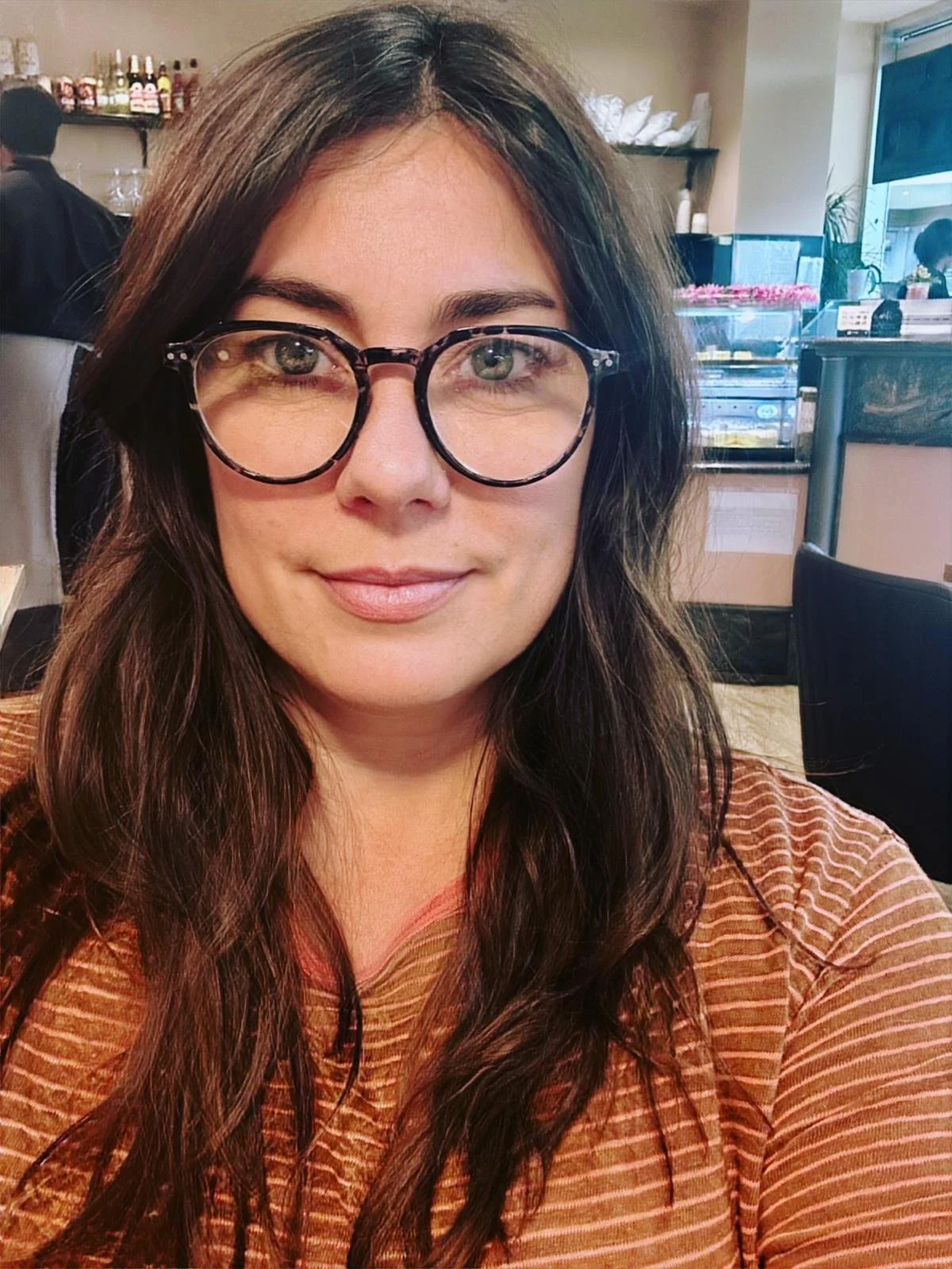 Das Portraitfoto zeigt Trudy True mit langen braunen Haaren und einer Lesebrille.