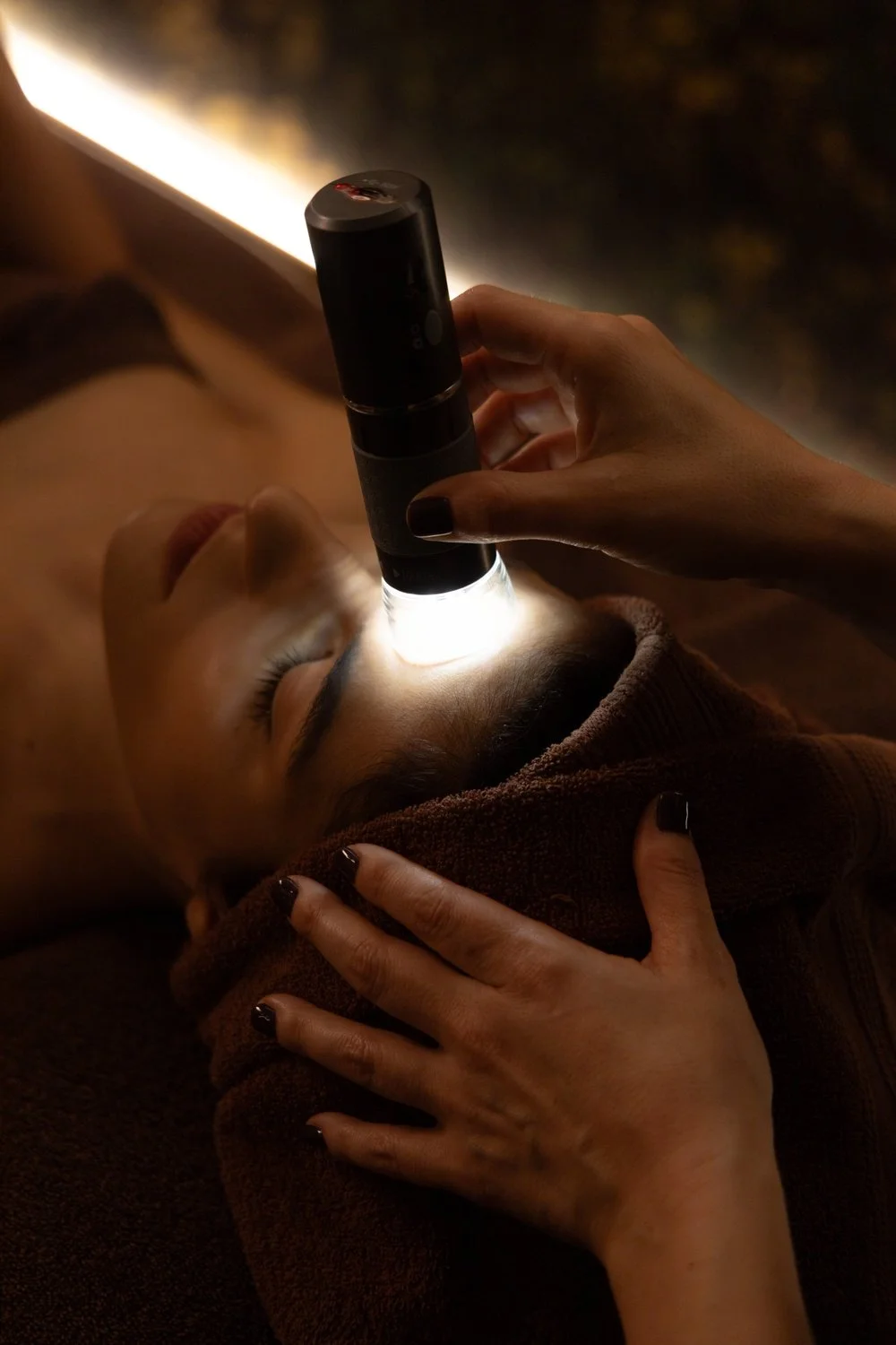 Professionista esegue un’analisi della pelle del viso con strumento luminoso durante un trattamento estetico a Padova