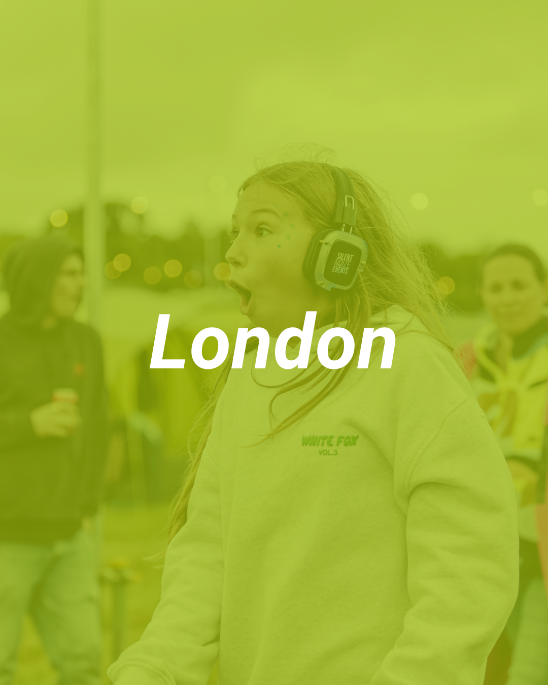 A young woman wearing headphones with a surprised or excited expression, standing outdoors in a group, with city lights in the background, overlaid with the word "London."