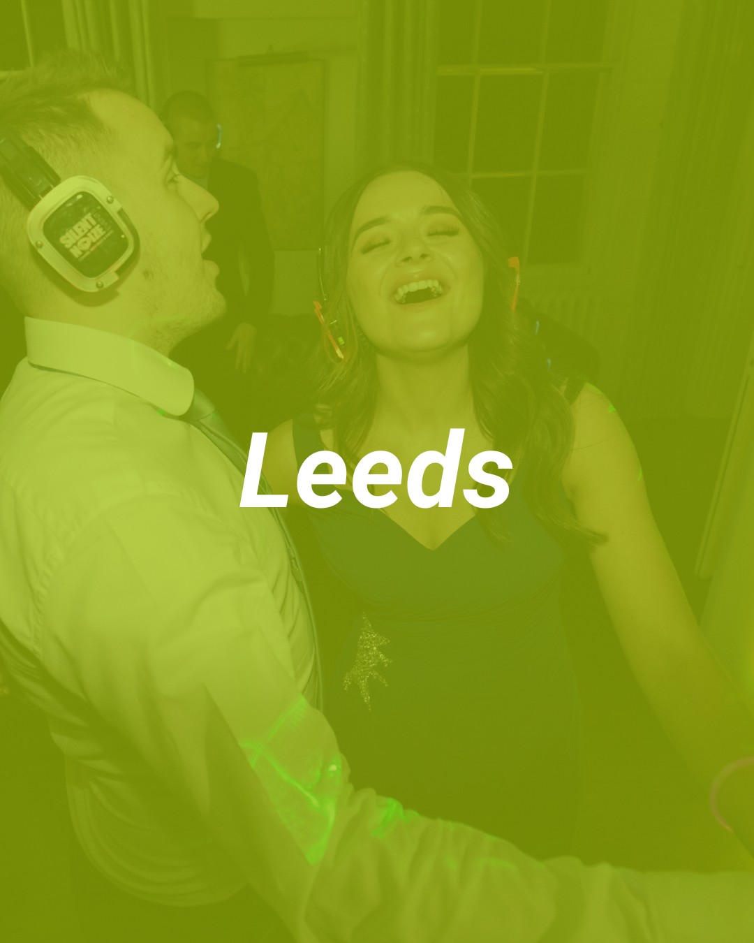 A woman with earrings dancing and singing joyfully while a DJ plays music at a party in Leeds.