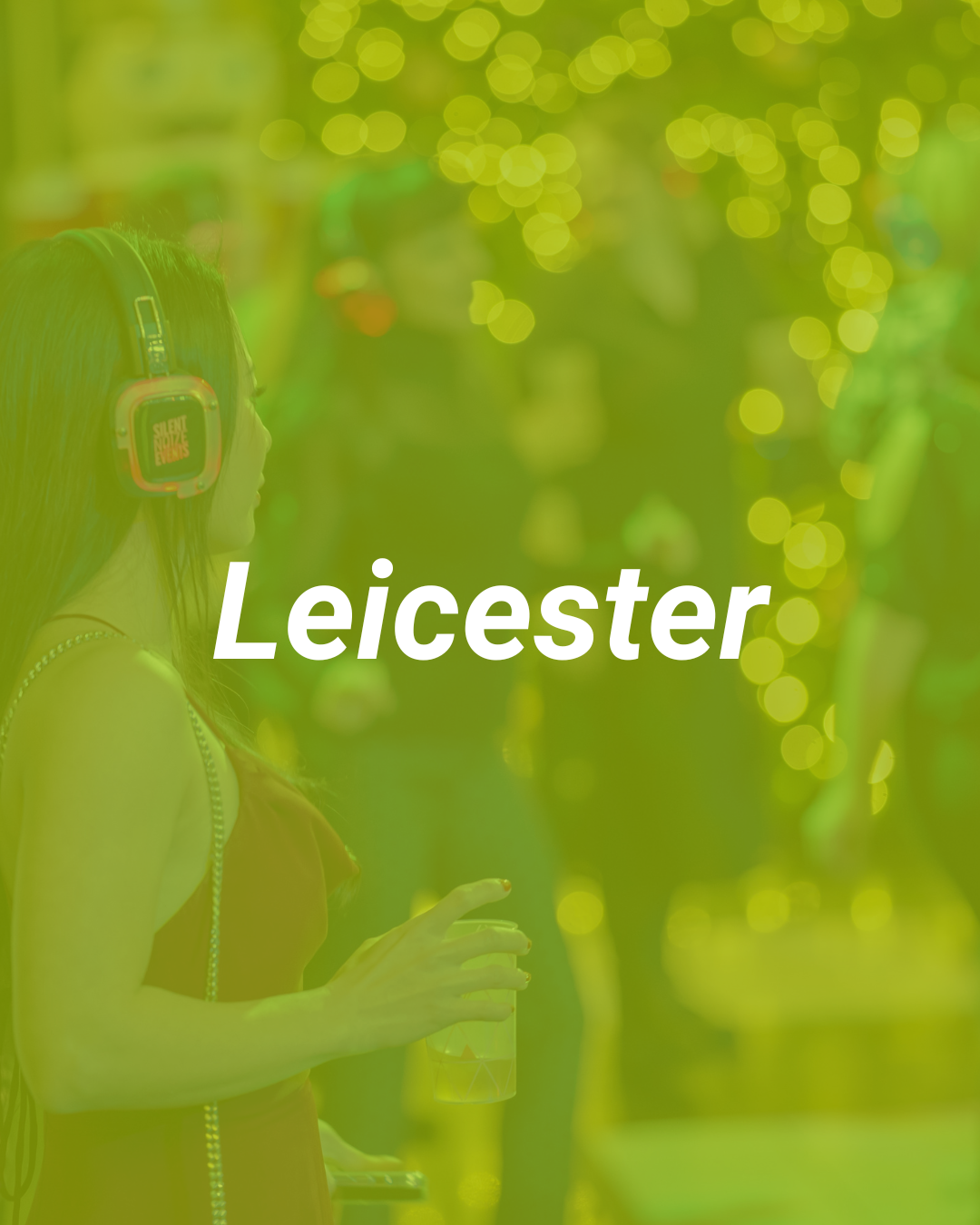 A woman with headphones listening to music at an outdoor event with green lighting and blurred background with bokeh lights. The text 'Leicester' is overlaid.
