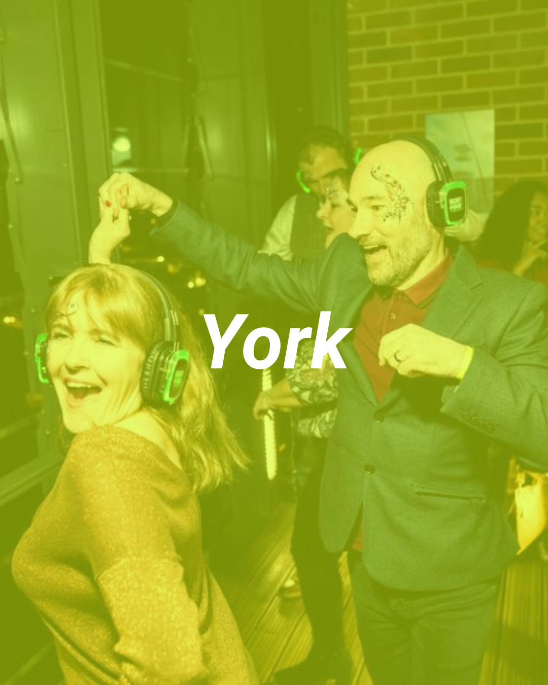 People dancing at a party with headphones, smiling and enjoying themselves in an indoor setting, with a brick wall in the background. The text 'York' is overlaid on the image.