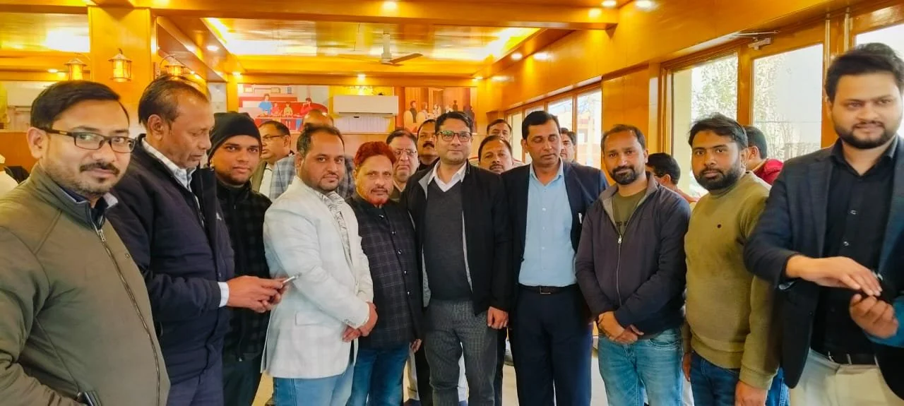 Group of men in casual and business attire gathered indoors for a photo, with warm lighting and wooden decor.
