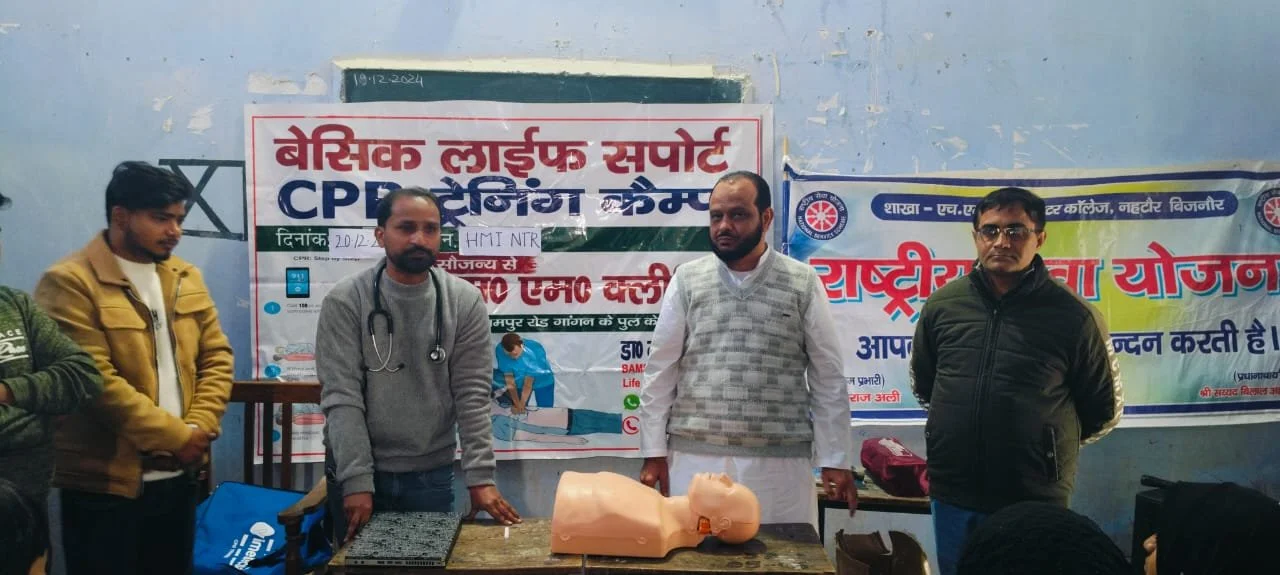 Group of men standing behind a CPR training mannequin at a health awareness event.