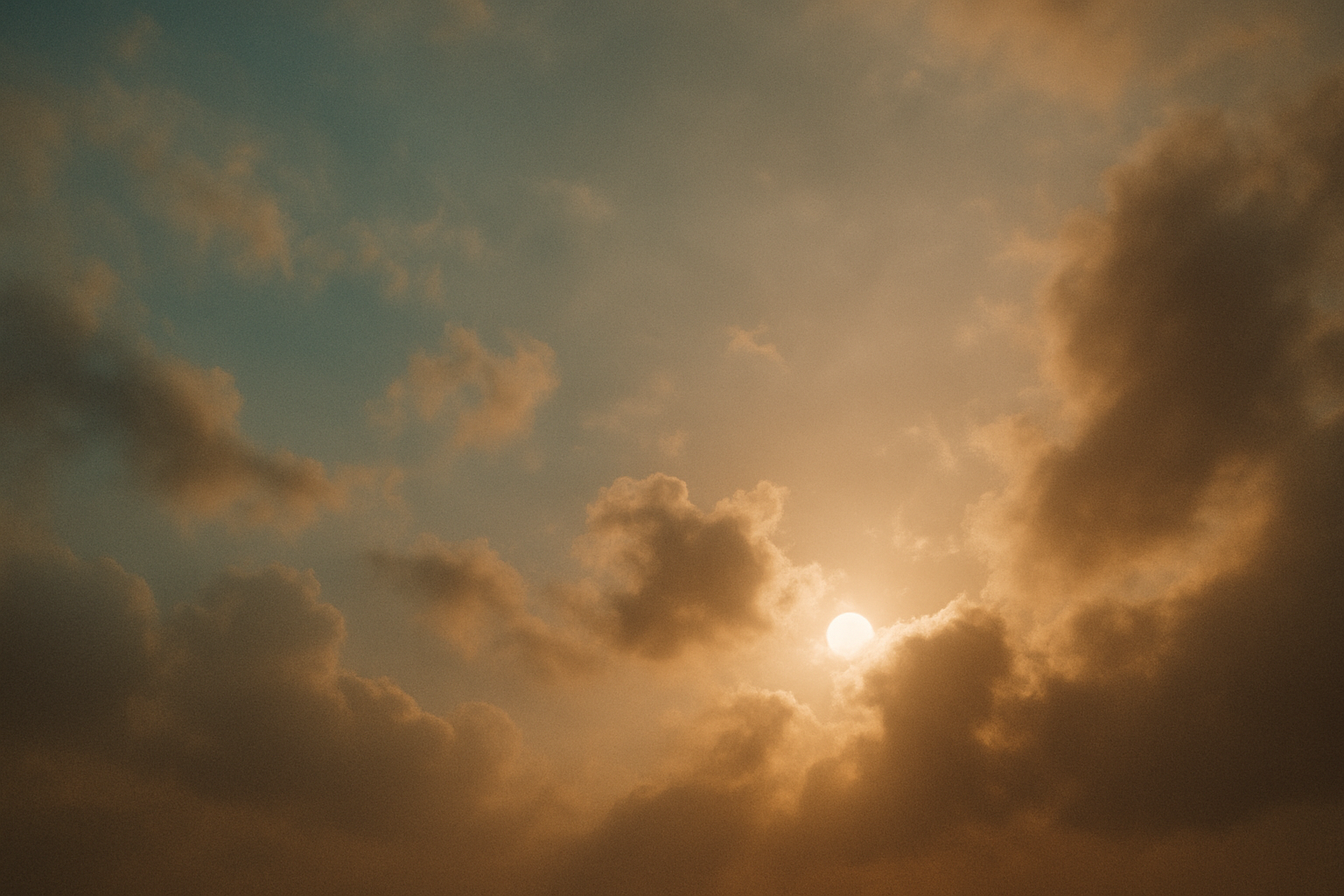 Sunlight breaking through clouds in a warm, atmospheric sky.