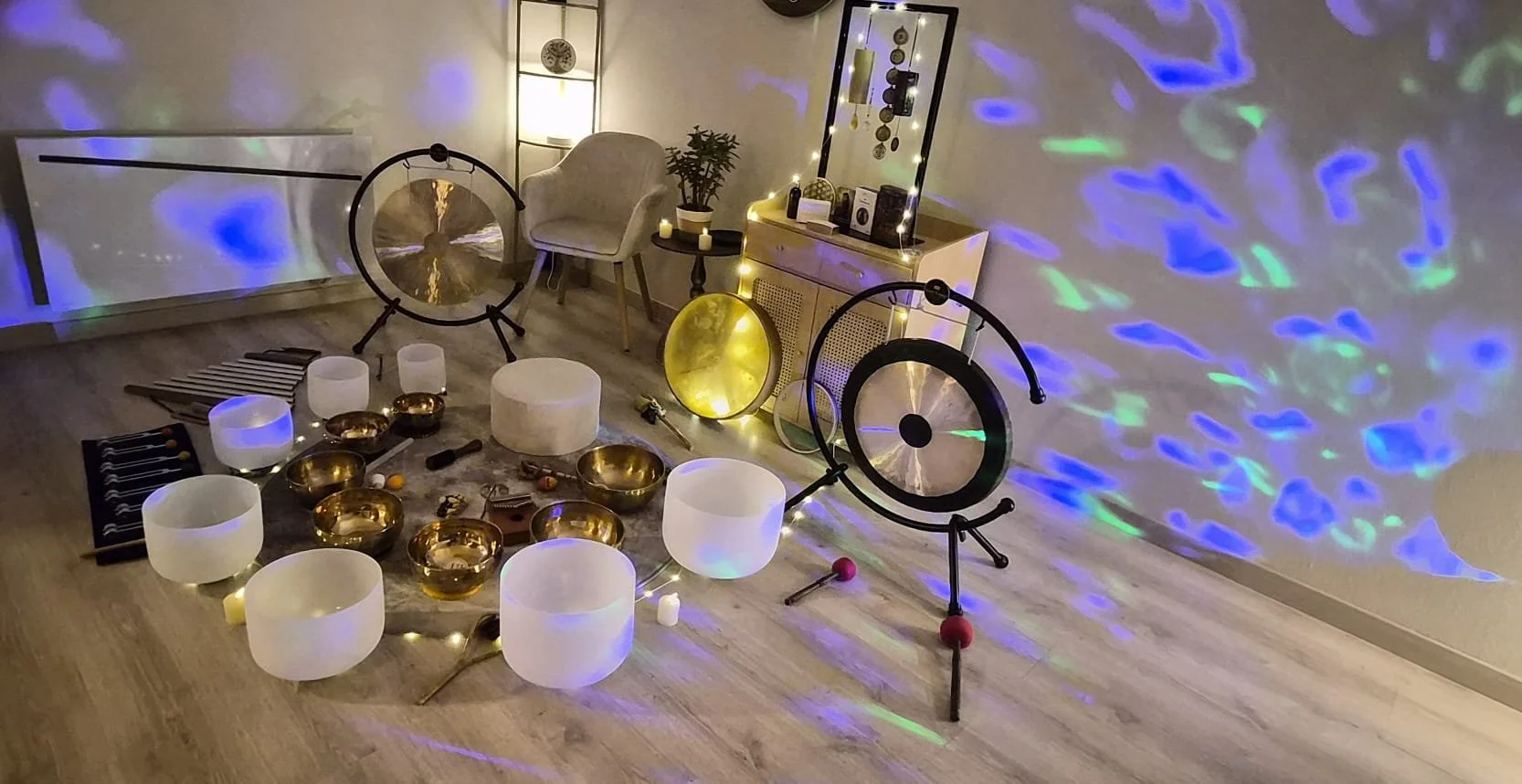 Une pièce décorée pour la relaxation avec des bols chantants, des gongs, et de la musique. L'éclairage d'ambiance crée des motifs colorés sur le mur.