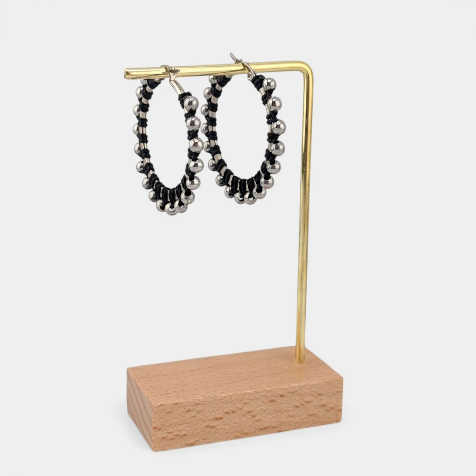 Black beaded macramé stainless steel hoop earrings in silver, 40 mm drop shown on earring display stand