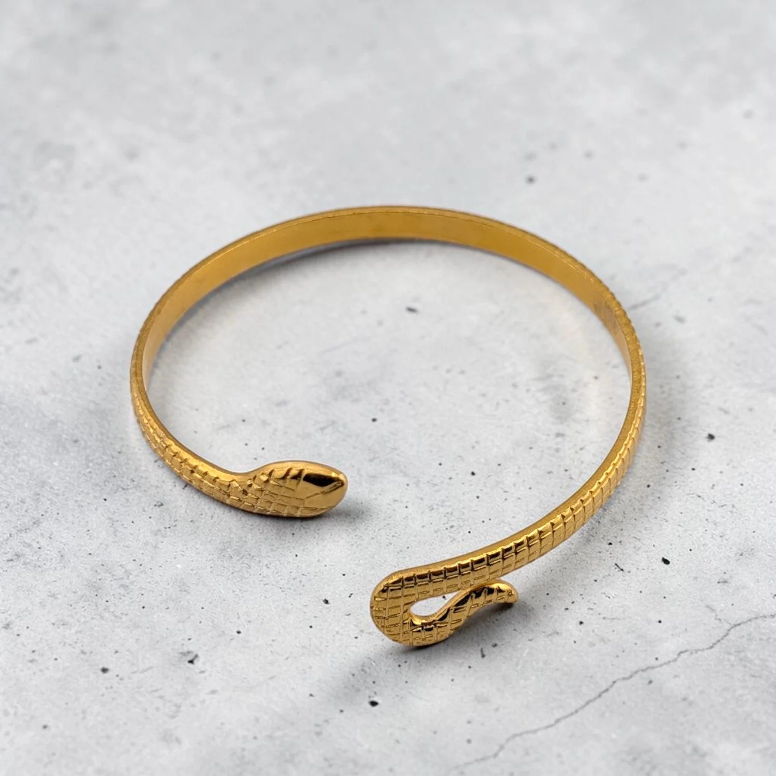 Gold snake stainless steel bangle bracelet, flat lay showing textured finish