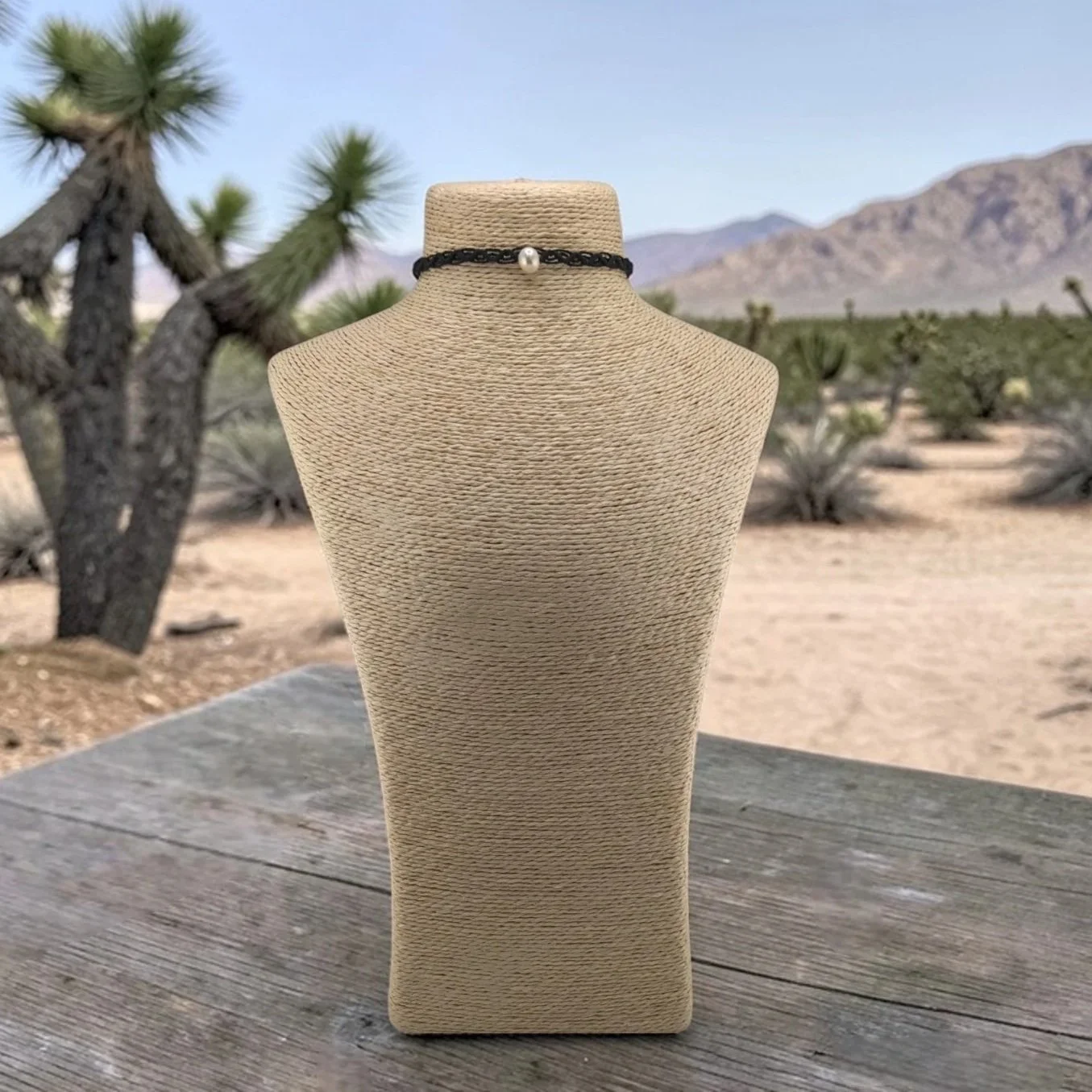 Freshwater pearl woven macrame choker displayed om a bust in a western desert-inspired outdoor setting