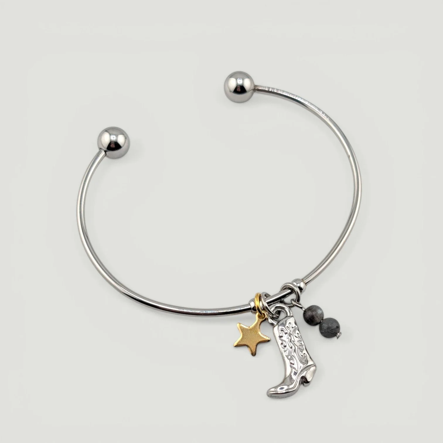 Silver cowboy boot stainless steel bangle bracelet with star and gemstone accents, full flat lay