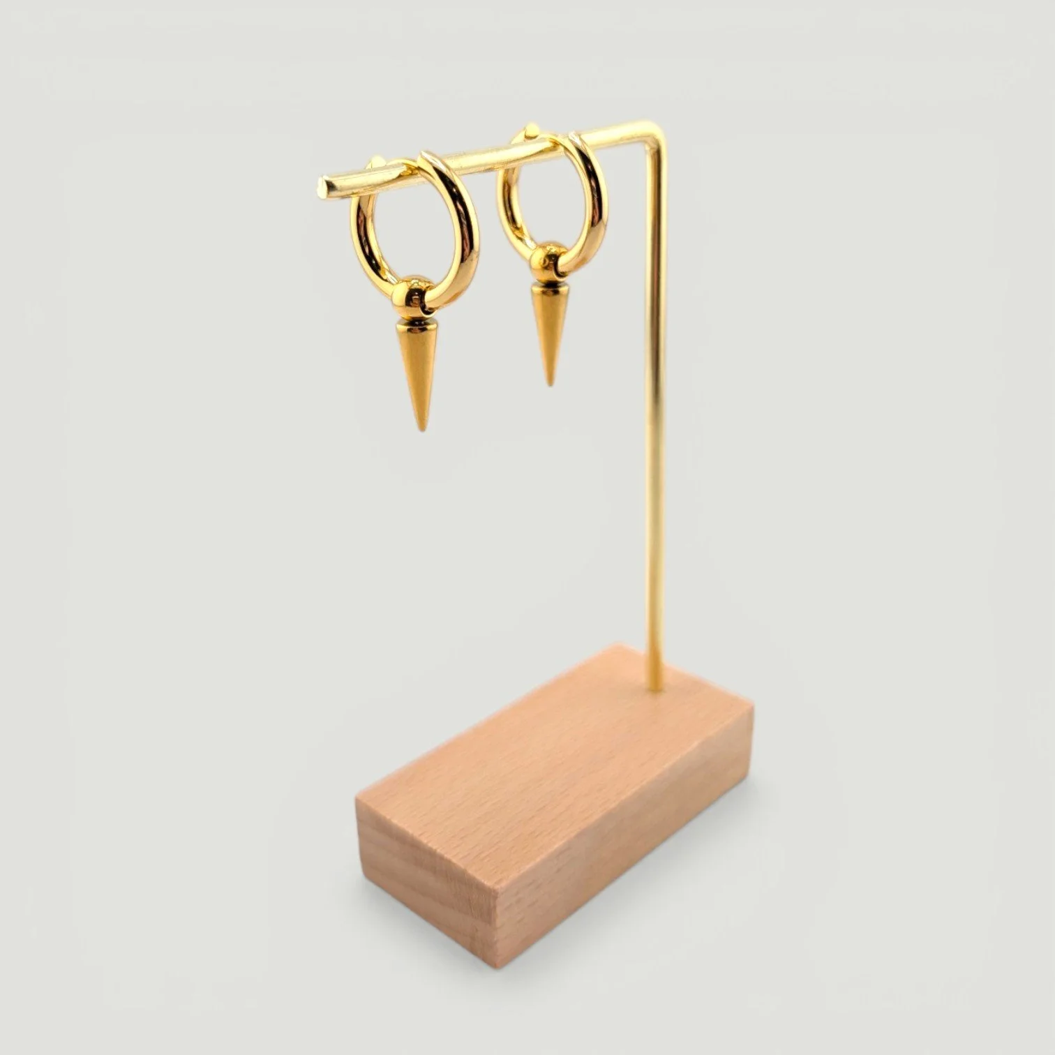 gold spike huggie hoop earrings on an earring stand, showing full drop and shine
