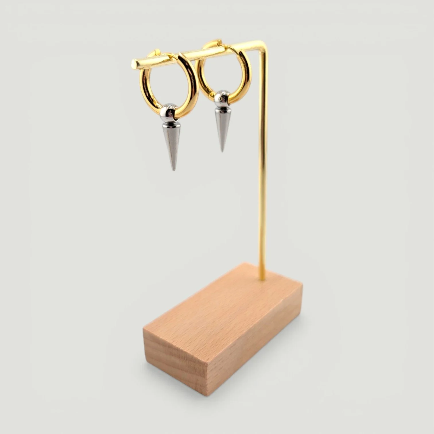 two-tone spike stainless steel huggie hoop earring on an earring stand, showing drop and shapen gold and silver