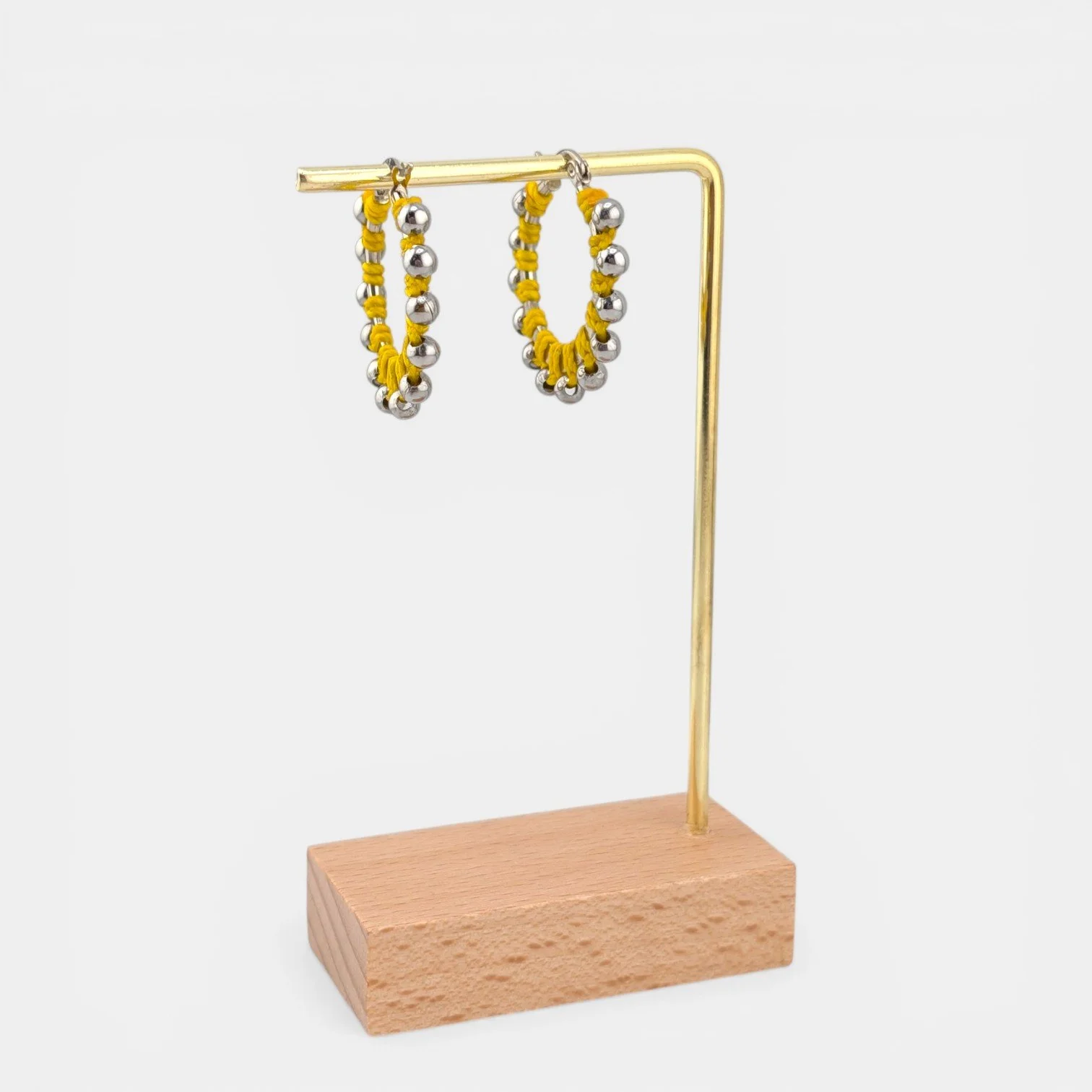 Yellow beaded macramé stainless steel hoop earrings in silver, 30 mm drop shown on earring display stand