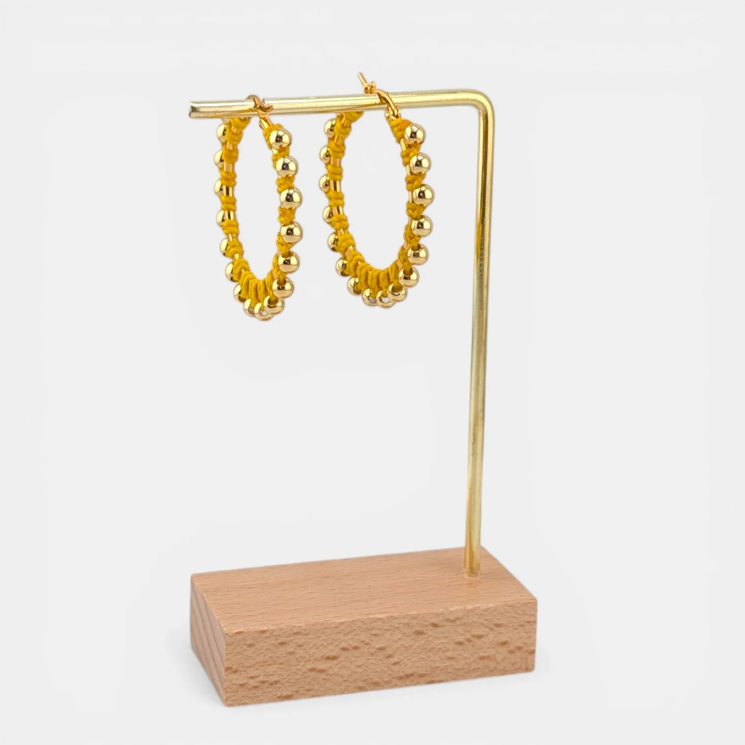yellow beaded macramé stainless steel hoop earrings in gold, 40 mm drop shown on earring display stand