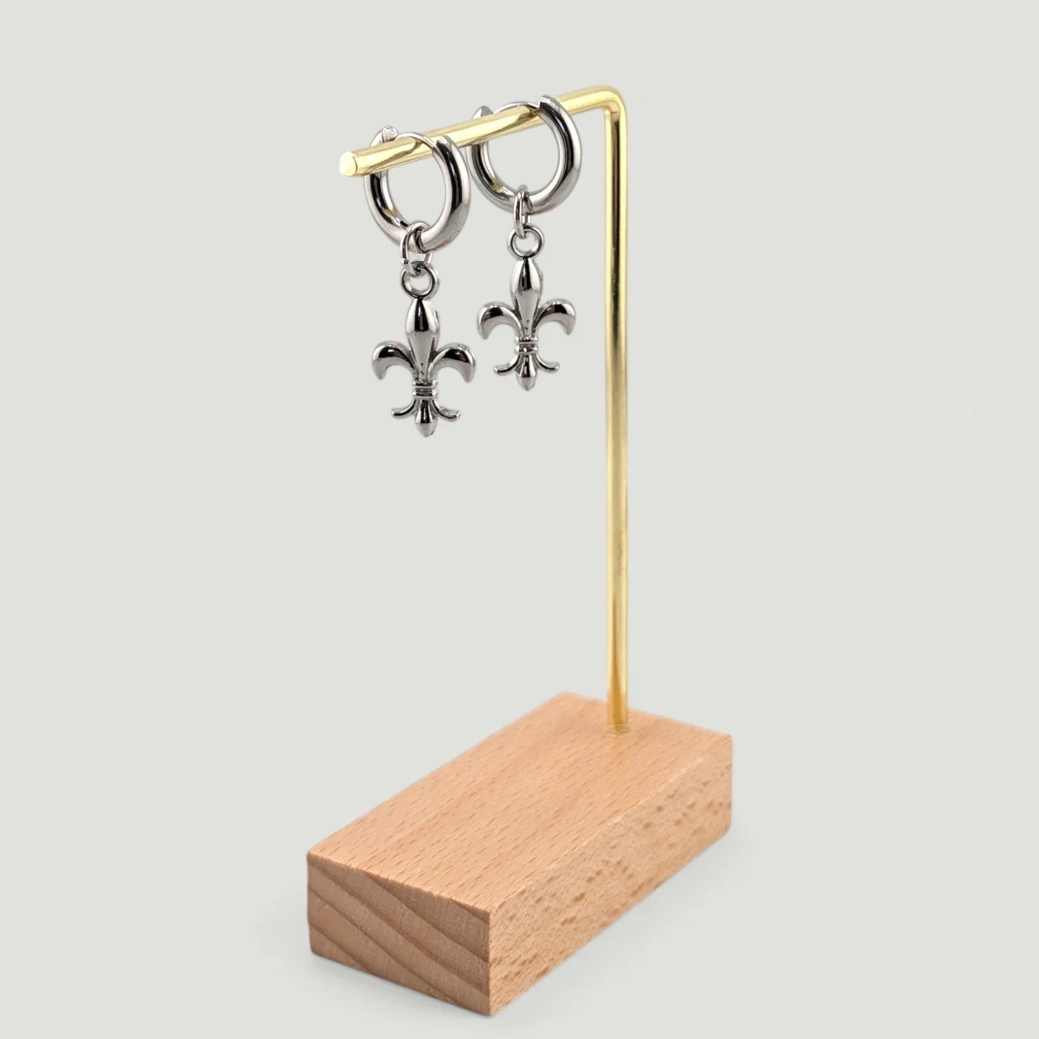 fleur de lis stainless steel huggie hoop earrings, silver, on earring stand, drop view