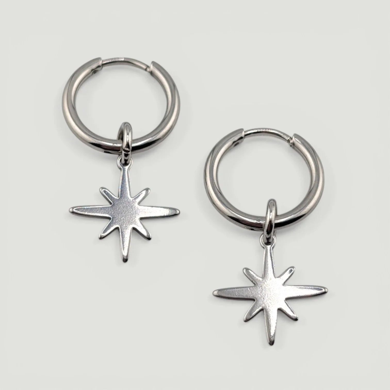 Silver stainless steel huggie hoop earrings with northern star charm flat lay