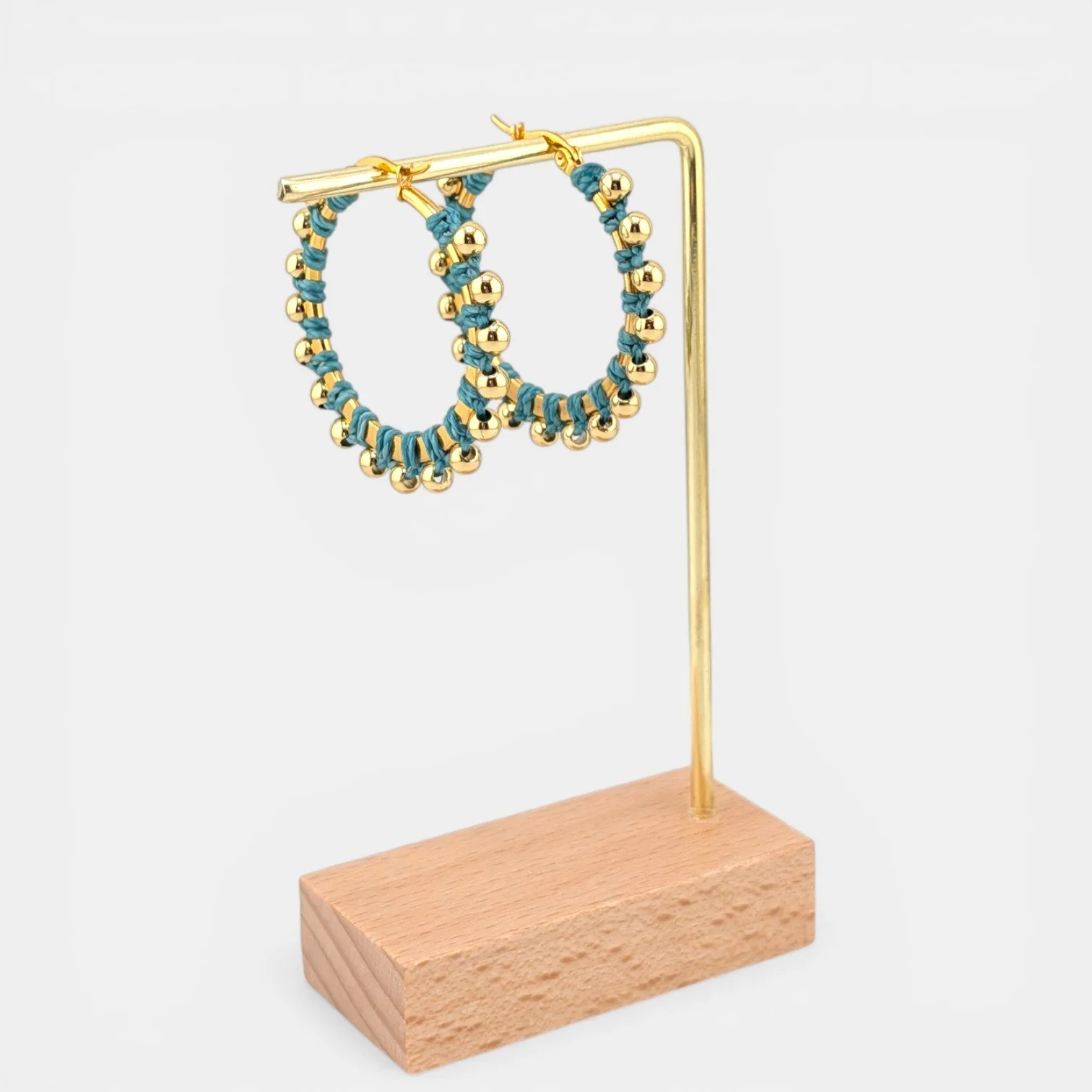 Turquoise beaded macramé stainless steel hoop earrings in gold, 40 mm drop shown on earring display stand