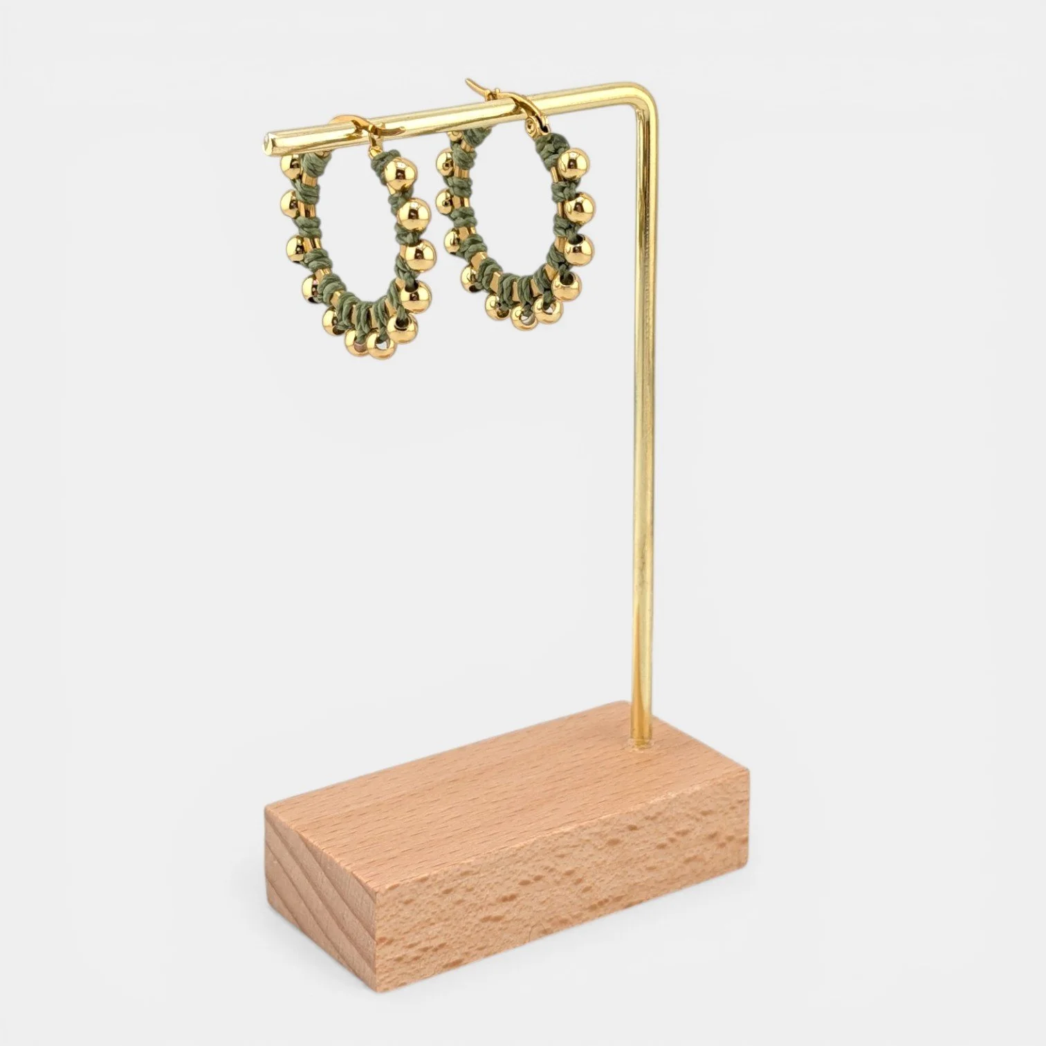 Light moss green beaded macramé stainless steel hoop earrings in gold, 30 mm drop shown on earring display stand