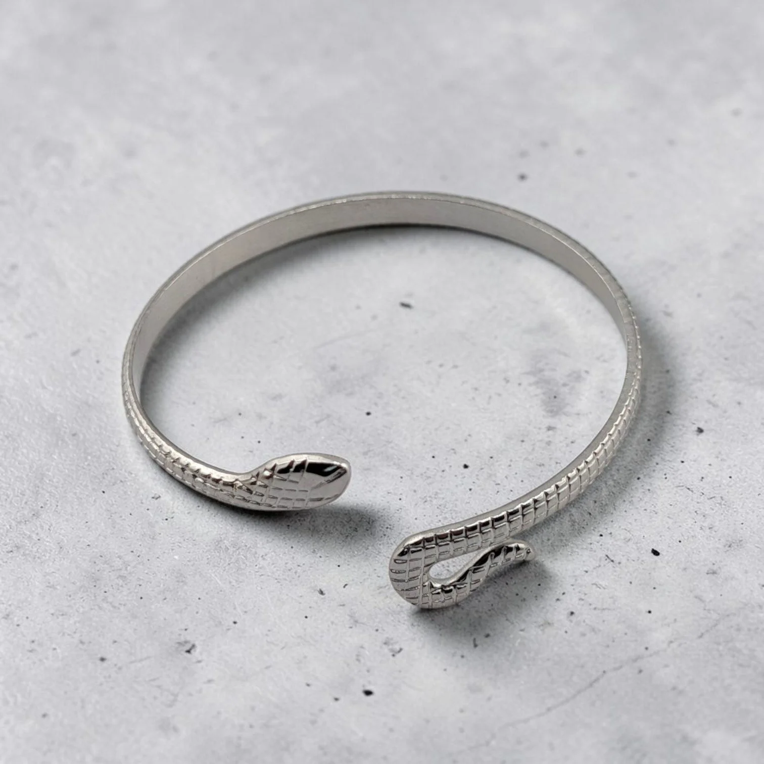 Silver snake stainless steel bangle bracelet, flat lay