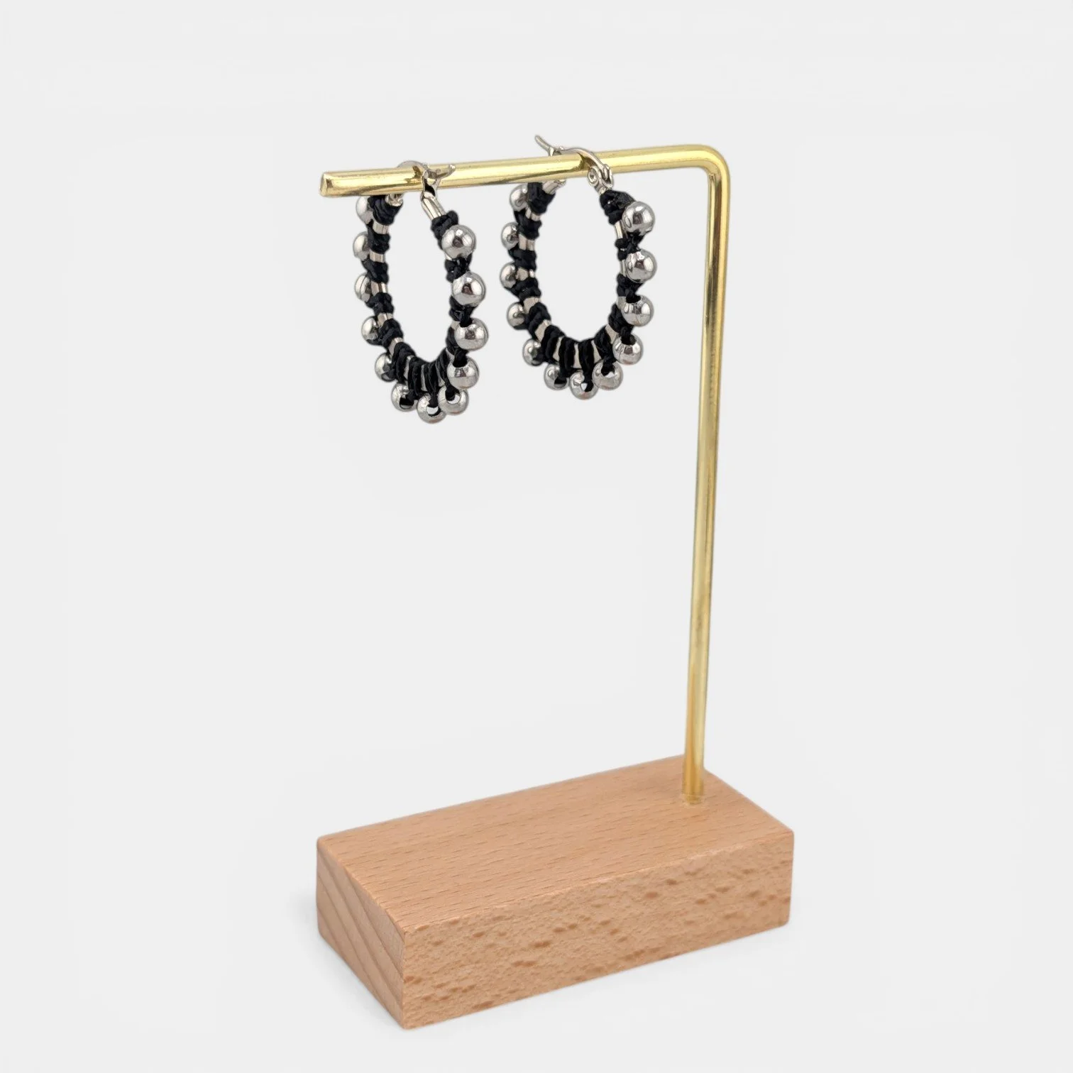 Black beaded macramé stainless steel hoop earrings in silver, 30 mm drop shown on earring display stand