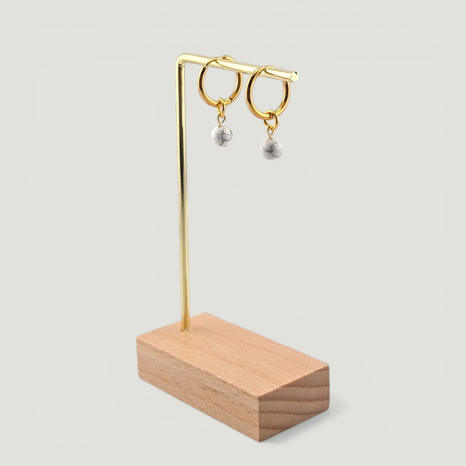 Howlite bead huggie hoop earrings hanging on display stand, stainless steel hoops, drop view
