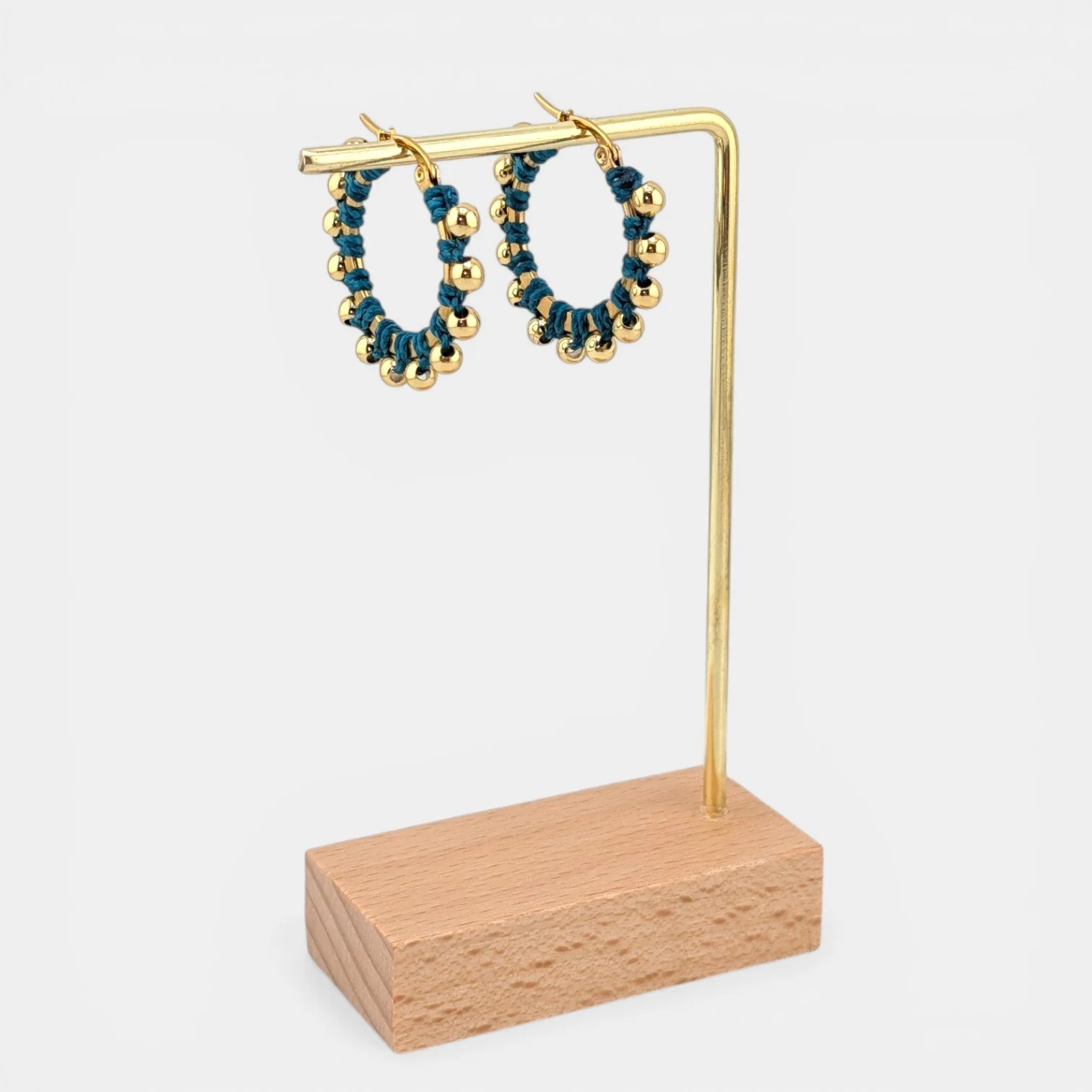 Teal beaded macramé stainless steel hoop earrings in gold, 30 mm drop shown on earring display stand