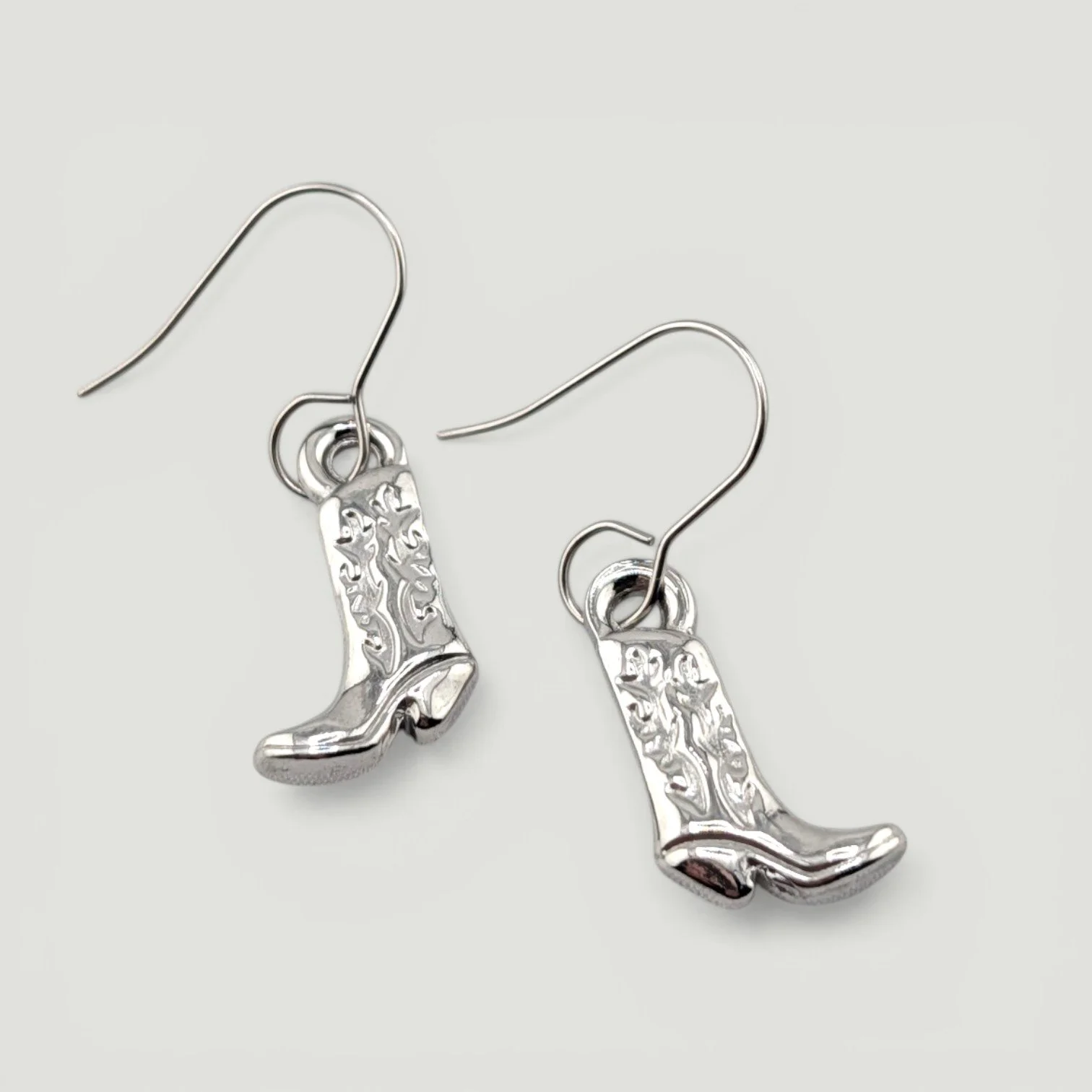 Silver stainless steel cowboy boot drop earrings flat lay showing detailed Western charm
