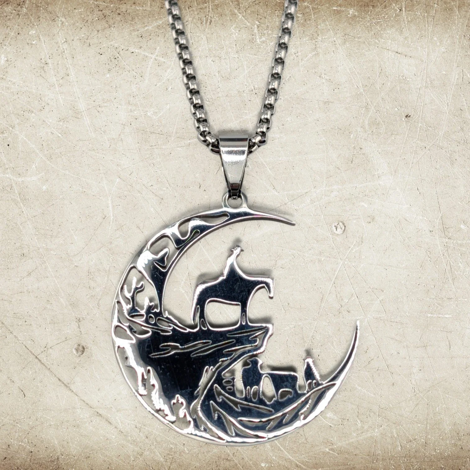 close-up flat lay of men's cowboy moon stainless steel necklace on a textured background