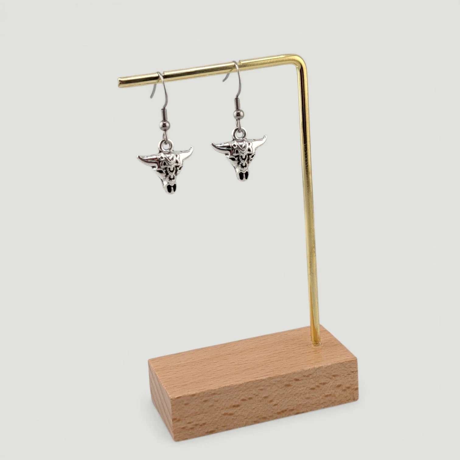 Bull skull drop earrings, silver tone, hanging on earring stand, full drop view