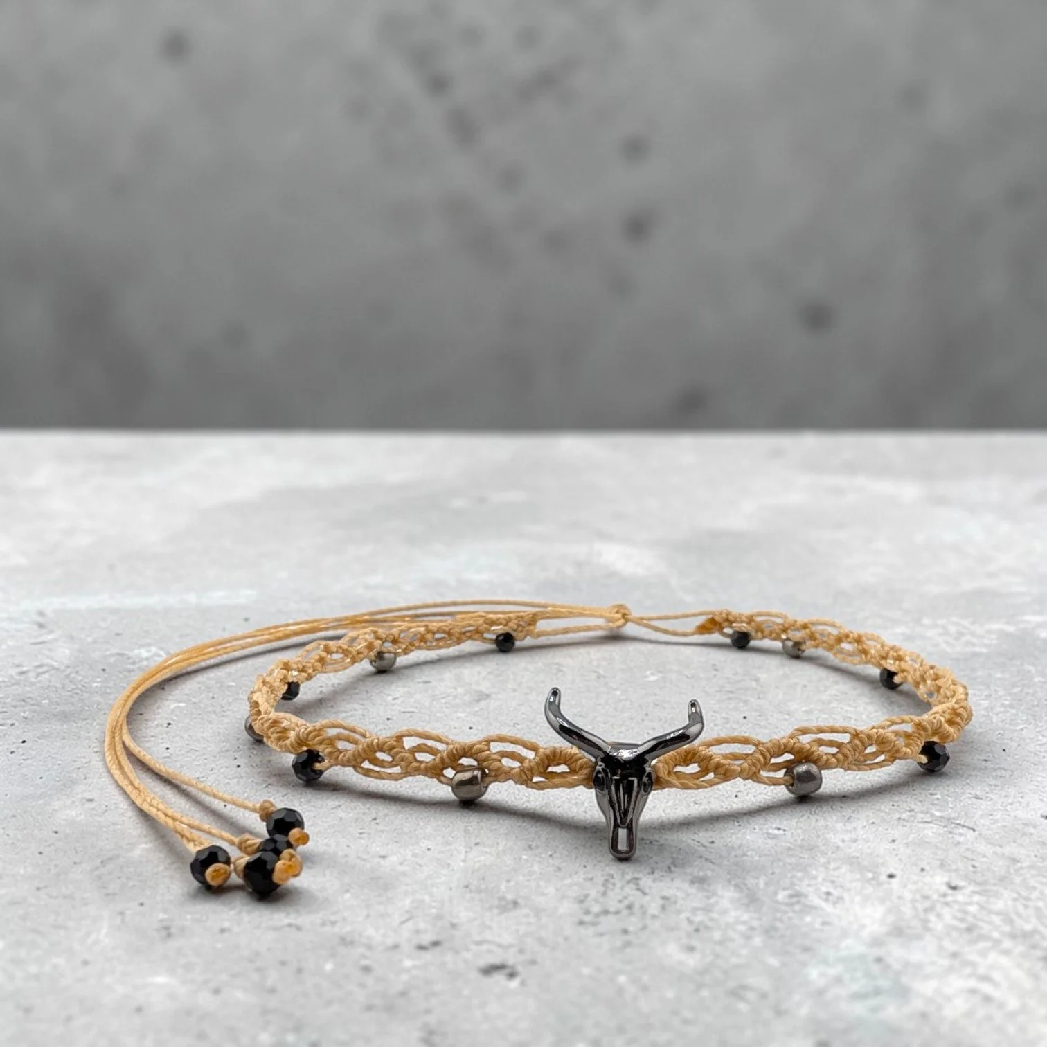 Gunmetal tone bull skull western macrame woven choker on a textured ciment shelf