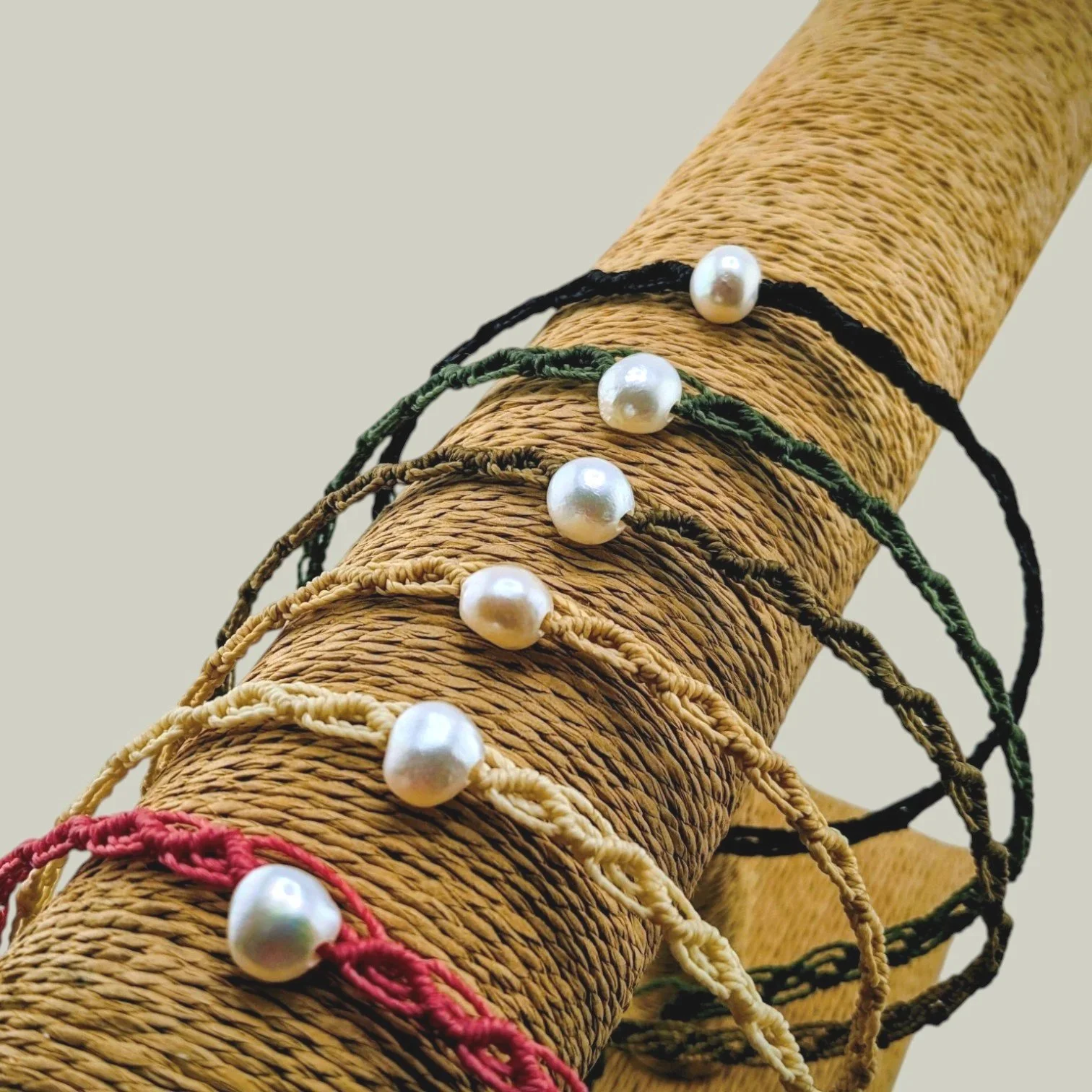 Freshwater pearl woven macrame chokers displayed on a t-bar stand showing six available cord colors