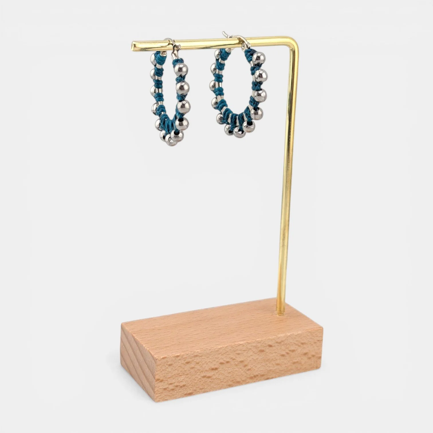 Teal beaded macramé stainless steel hoop earrings in silver, 30 mm drop shown on earring display stand